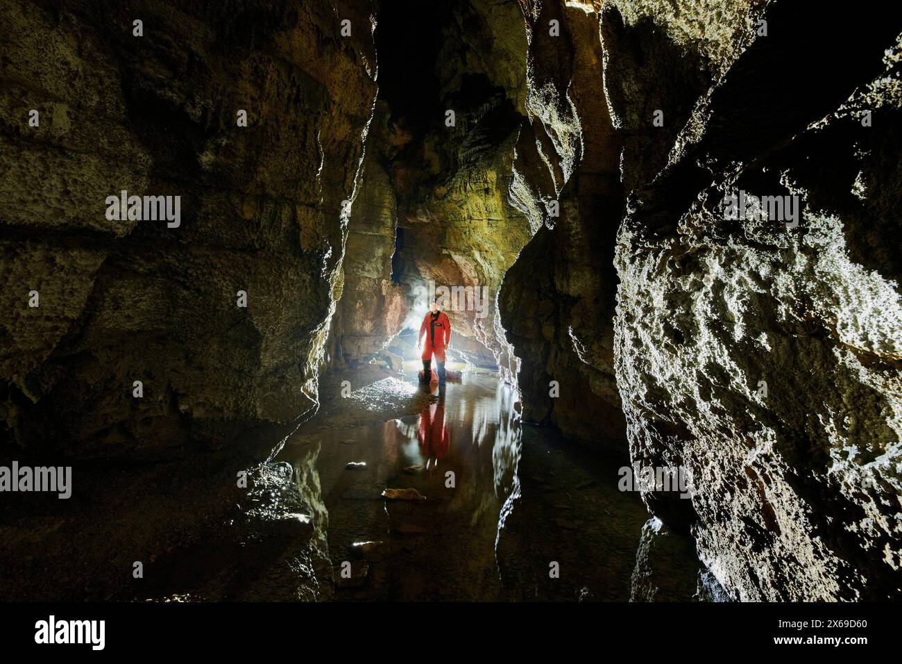 Speleologo in una grotta, fiume sotterraneo con riflessi Foto Stock