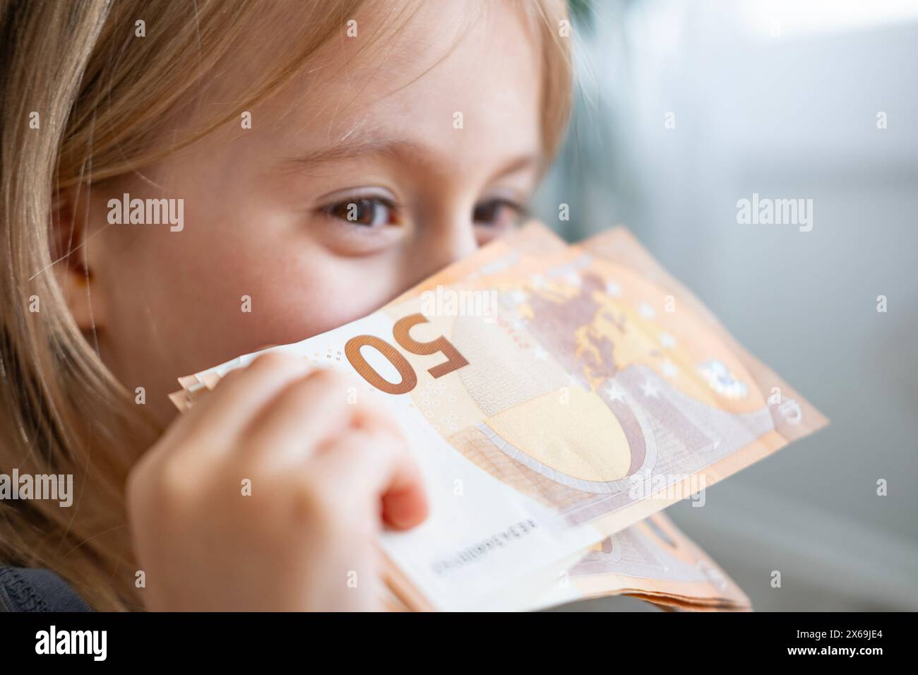 bambina, ragazza allegra, ha 50 banconote da primo piano, l'immaginazione ha acceso la moneta di potere, la consapevolezza finanziaria, giovane felice Foto Stock
