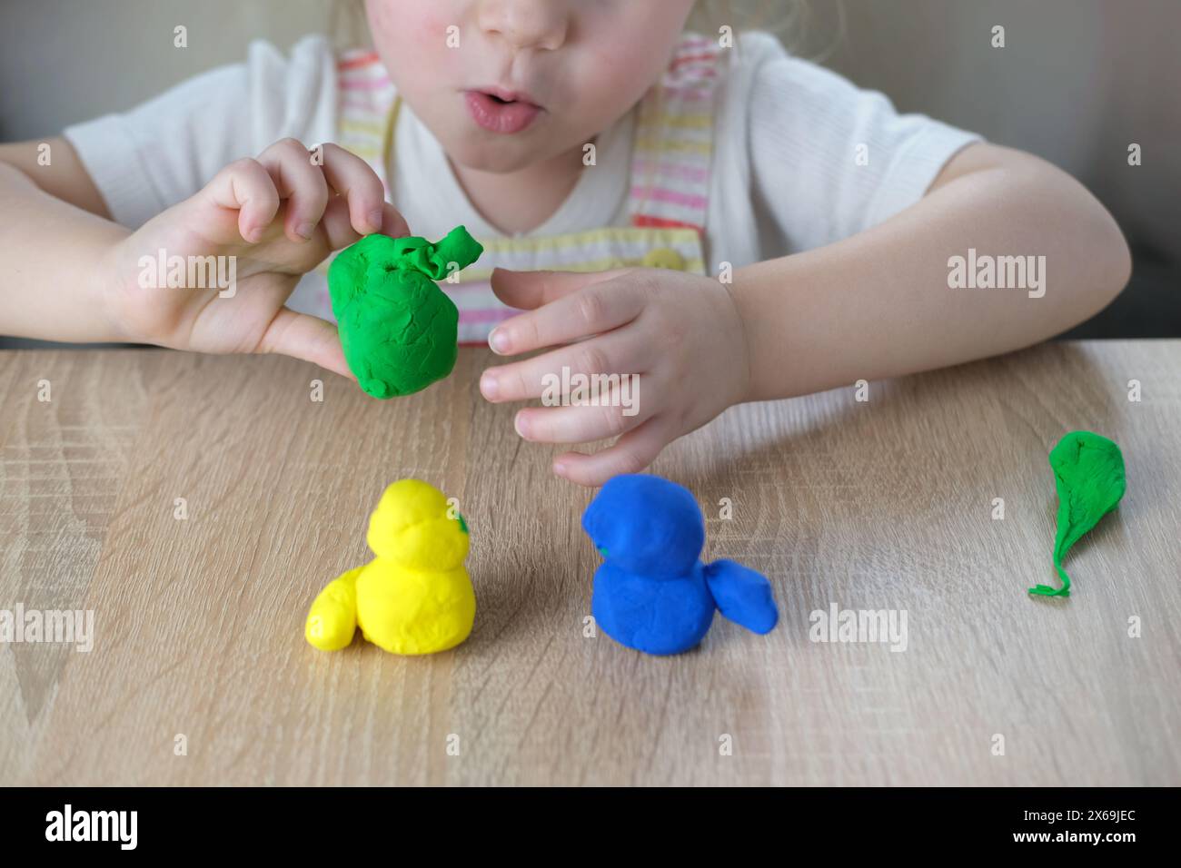 giocattoli in plastica per primi piani nelle mani di bimbi piccoli, bimbi piccoli, bionda di 2 anni scolpisce figure di personaggi di impasto colorato, concetto di fine m Foto Stock