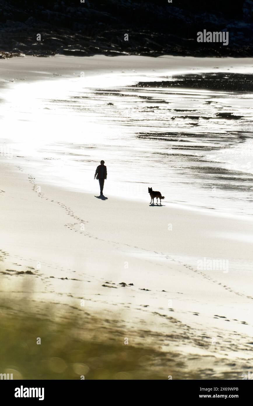 Spiaggia di Hosta sulla costa occidentale di North Uist, Ebridi esterne, Scozia. Donna e cane che camminano sulla sabbia Foto Stock