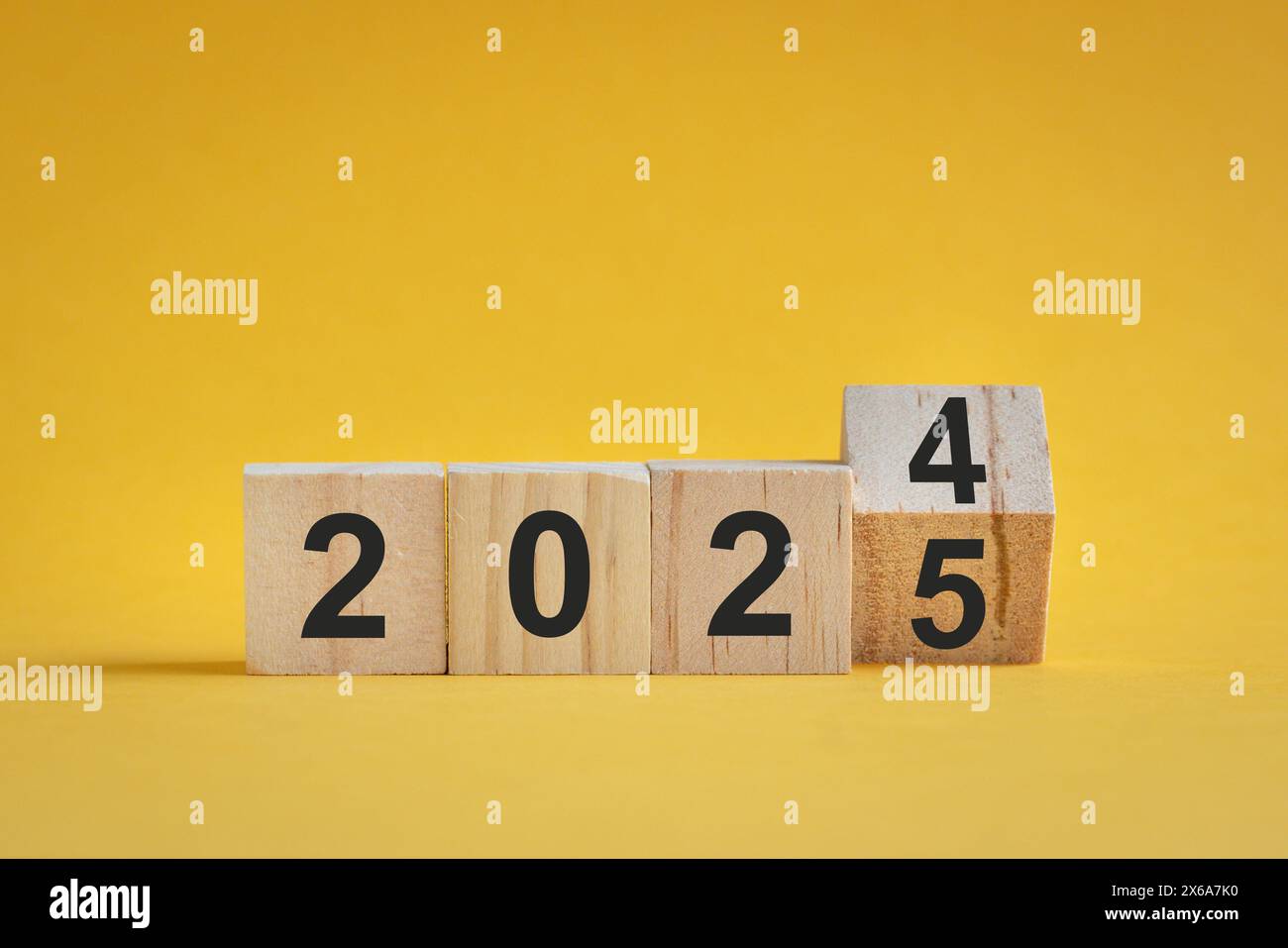 Dal 2024 al 2025, numeri su blocchi di legno. Su sfondo giallo, concetto di anno nuovo. Foto Stock