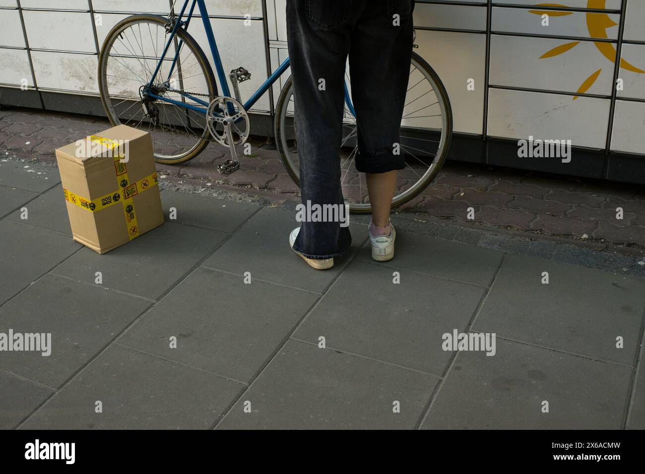 Una donna con una gamba arrotolata viene vista con un pacco e una bicicletta in un armadietto a Varsavia, in Polonia, il 13 maggio 2024. Foto Stock