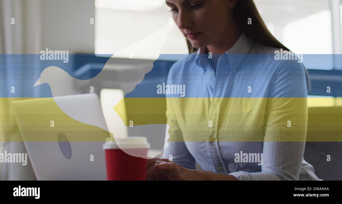 Una donna professionista caucasica, che tiene in mano una tazza rossa, che utilizza un notebook Foto Stock