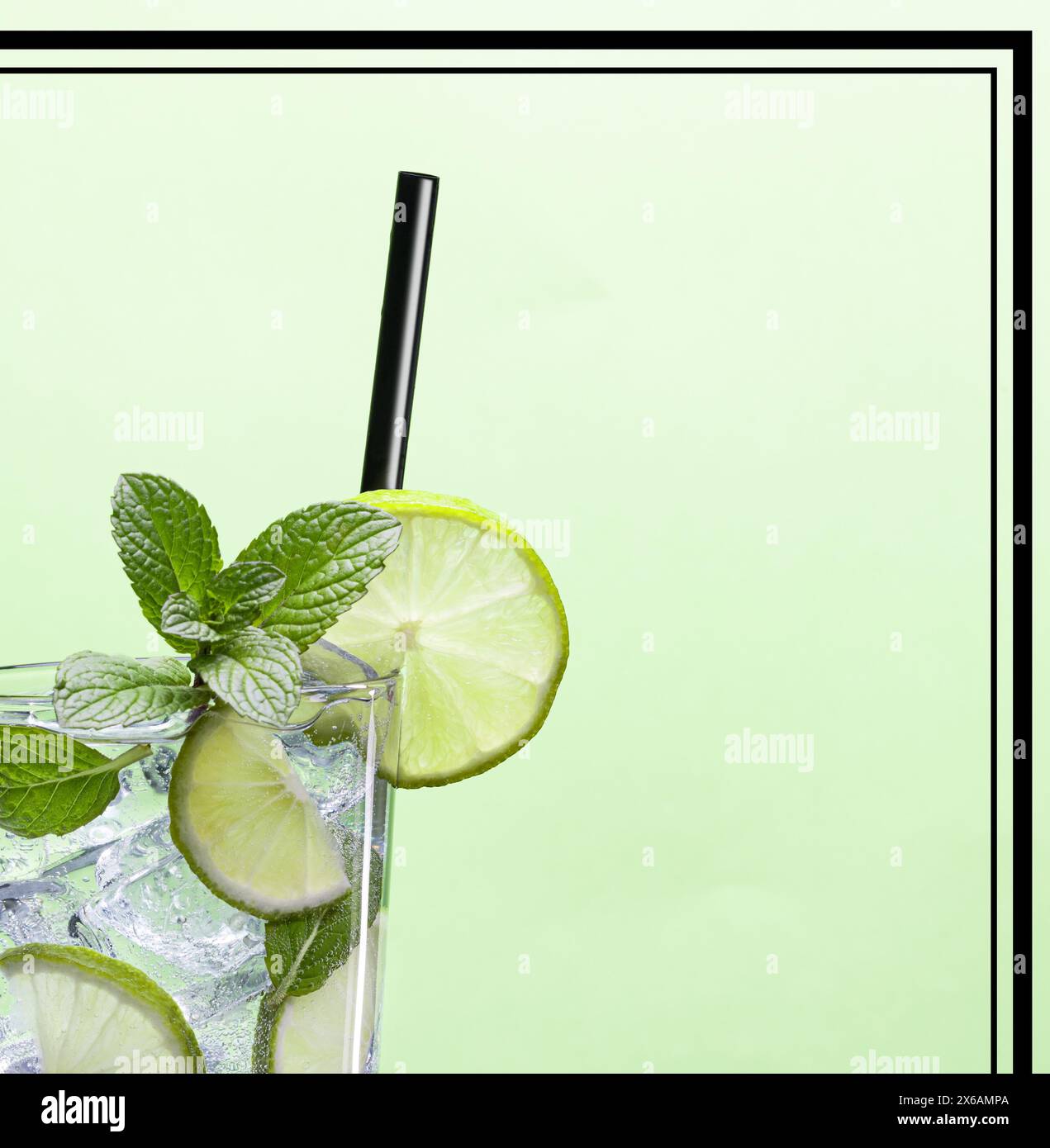 Vista ritagliata del cocktail Mojito con menta, lime e cannuccia nera su sfondo verde incorniciato. Immagine pubblicitaria cocktail bar. Foto Stock