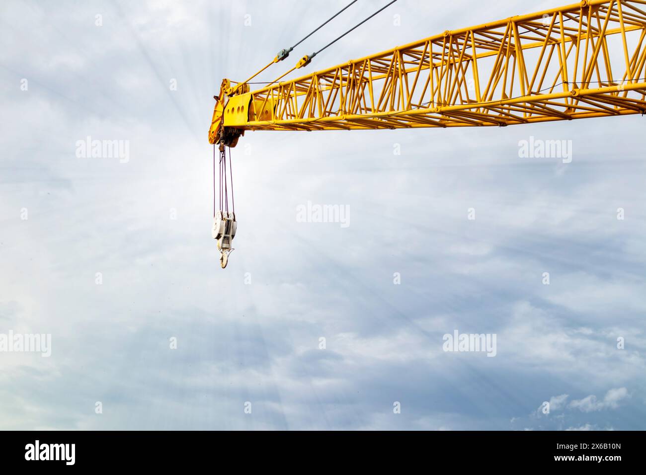 sul sollevamento del braccio della gru in cantiere e sul cielo blu, sottolineando i dettagli e l'imbracatura della gru Foto Stock