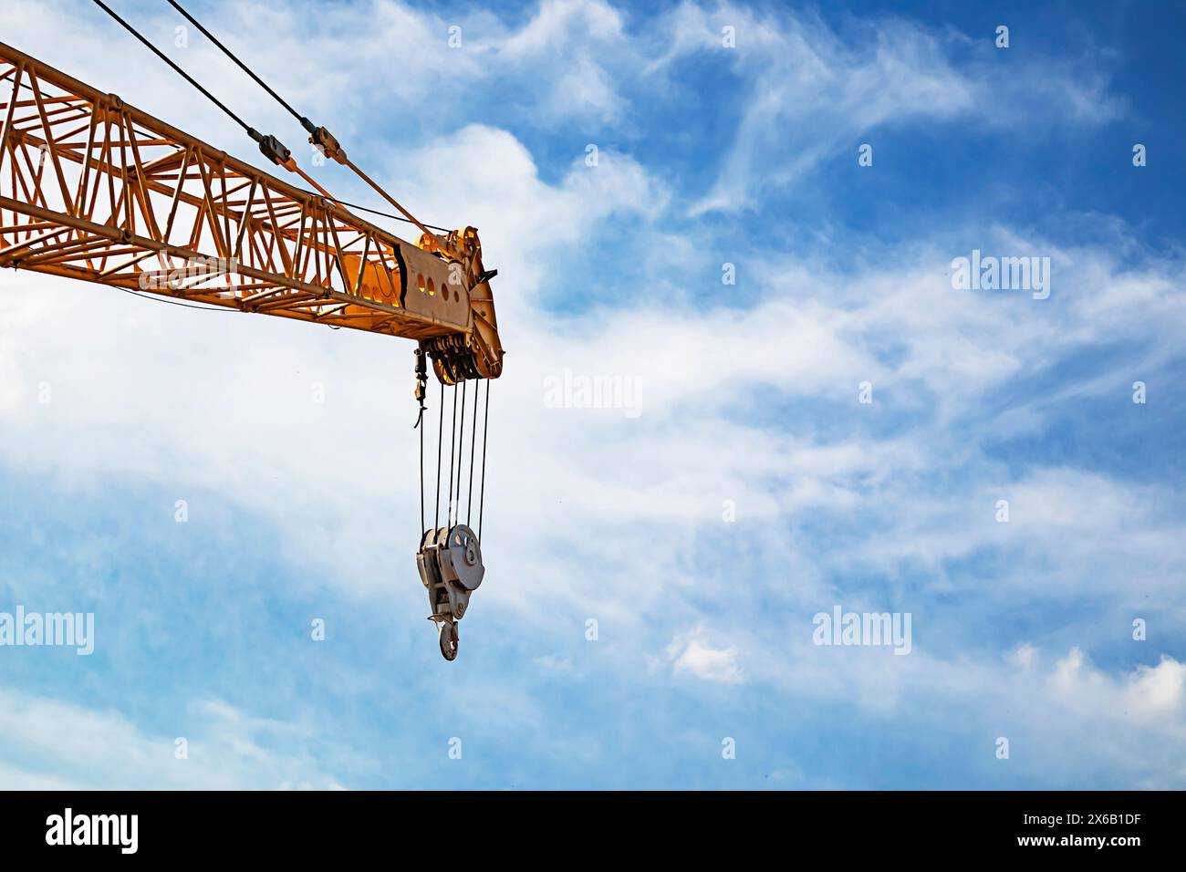 sul sollevamento del braccio della gru in cantiere e sul cielo blu, sottolineando i dettagli e l'imbracatura della gru Foto Stock