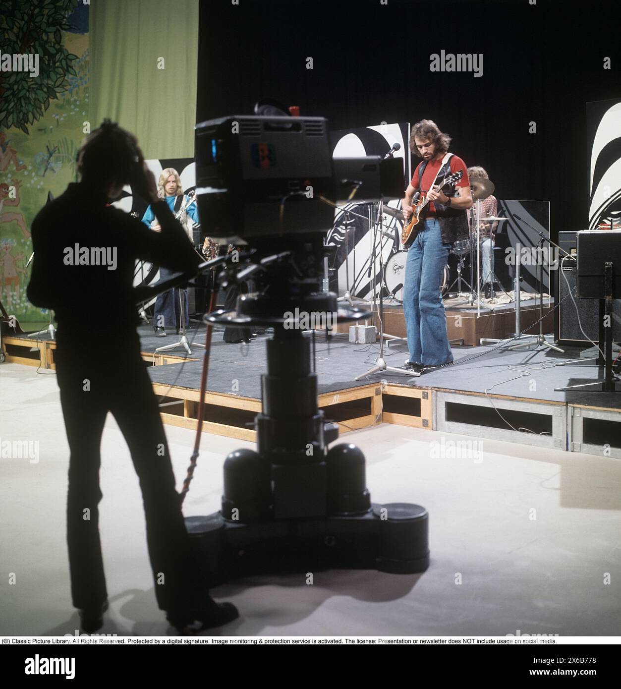 Moda degli anni '1970 Un giovane uomo che indossa la tipica moda degli anni '1970, pantaloni a gambe larghe. Uno stile chiamato campana o zampe, pantaloni che si allargano dalle ginocchia e verso il basso, formando una forma a campana della gamba dei pantaloni. È il musicista Claes af Geijerstam con la sua band Marsfolket in uno studio televisivo che registra un programma. 1971. Svahn Foto Stock