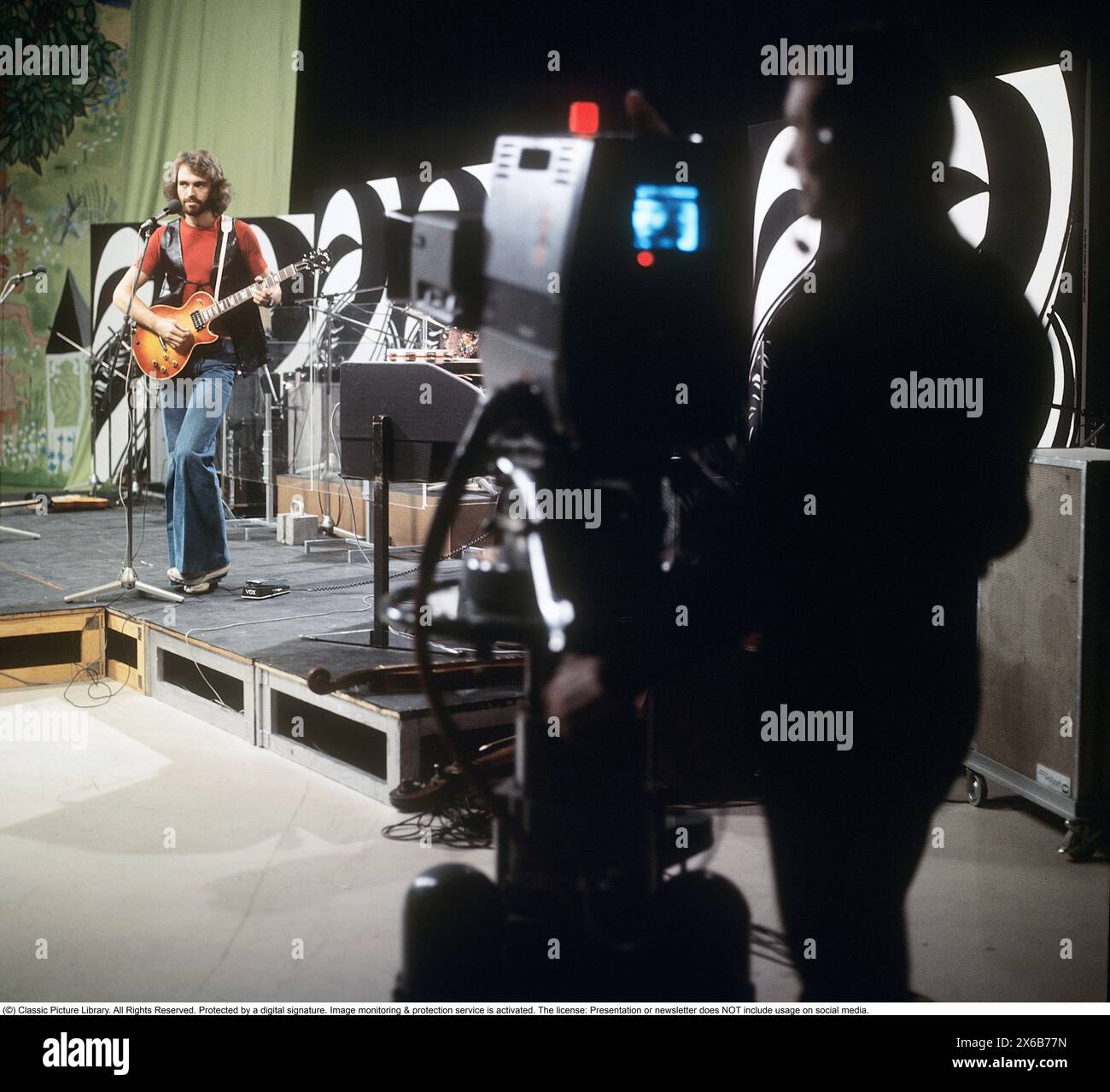 Moda degli anni '1970 Un giovane uomo che indossa la tipica moda degli anni '1970, pantaloni a gambe larghe. Uno stile chiamato campana o zampe, pantaloni che si allargano dalle ginocchia e verso il basso, formando una forma a campana della gamba dei pantaloni. È il musicista Claes af Geijerstam con la sua band Marsfolket in uno studio televisivo che registra un programma. 1971. Svahn Foto Stock