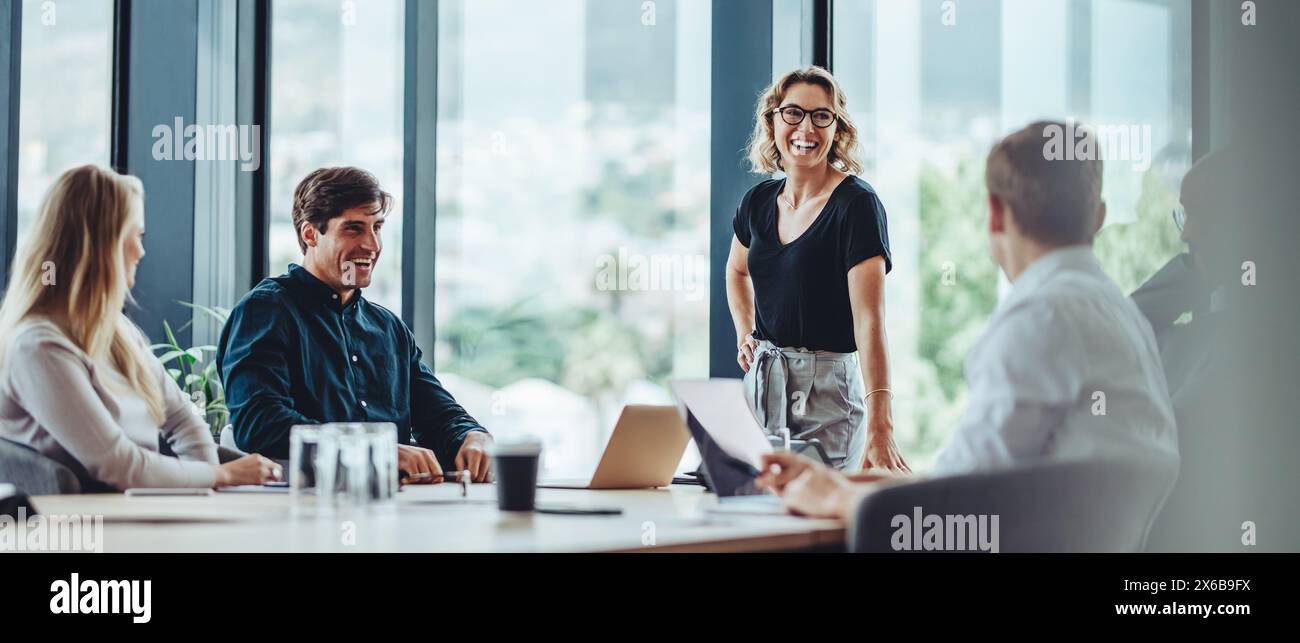 Gruppo di colleghi impegnati in una discussione durante una riunione di lavoro in una sala conferenze. Uomini d'affari felici, uomini e donne, collaborando e W Foto Stock
