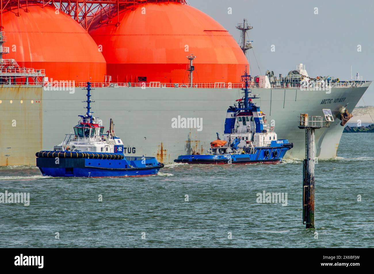 Rotterdam, Paesi Bassi, 13 aprile 2024: Due rimorchiatori in procinto di collegarsi ad una grande cisterna GNL in viaggio verso il terminal Foto Stock