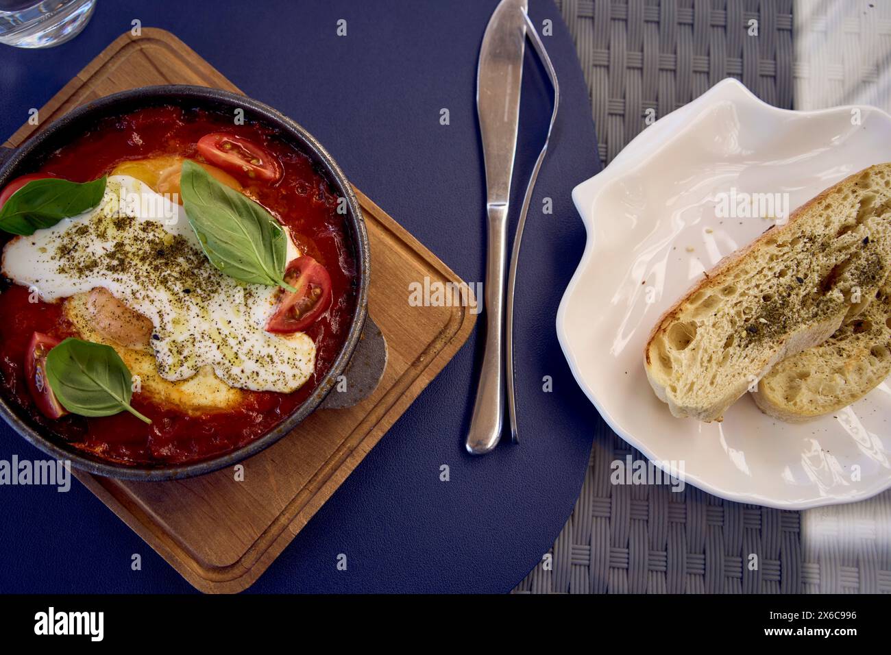 Una donna di medie dimensioni in un abito da pesca che mangia Shakshouka in un ristorante moderno Foto Stock