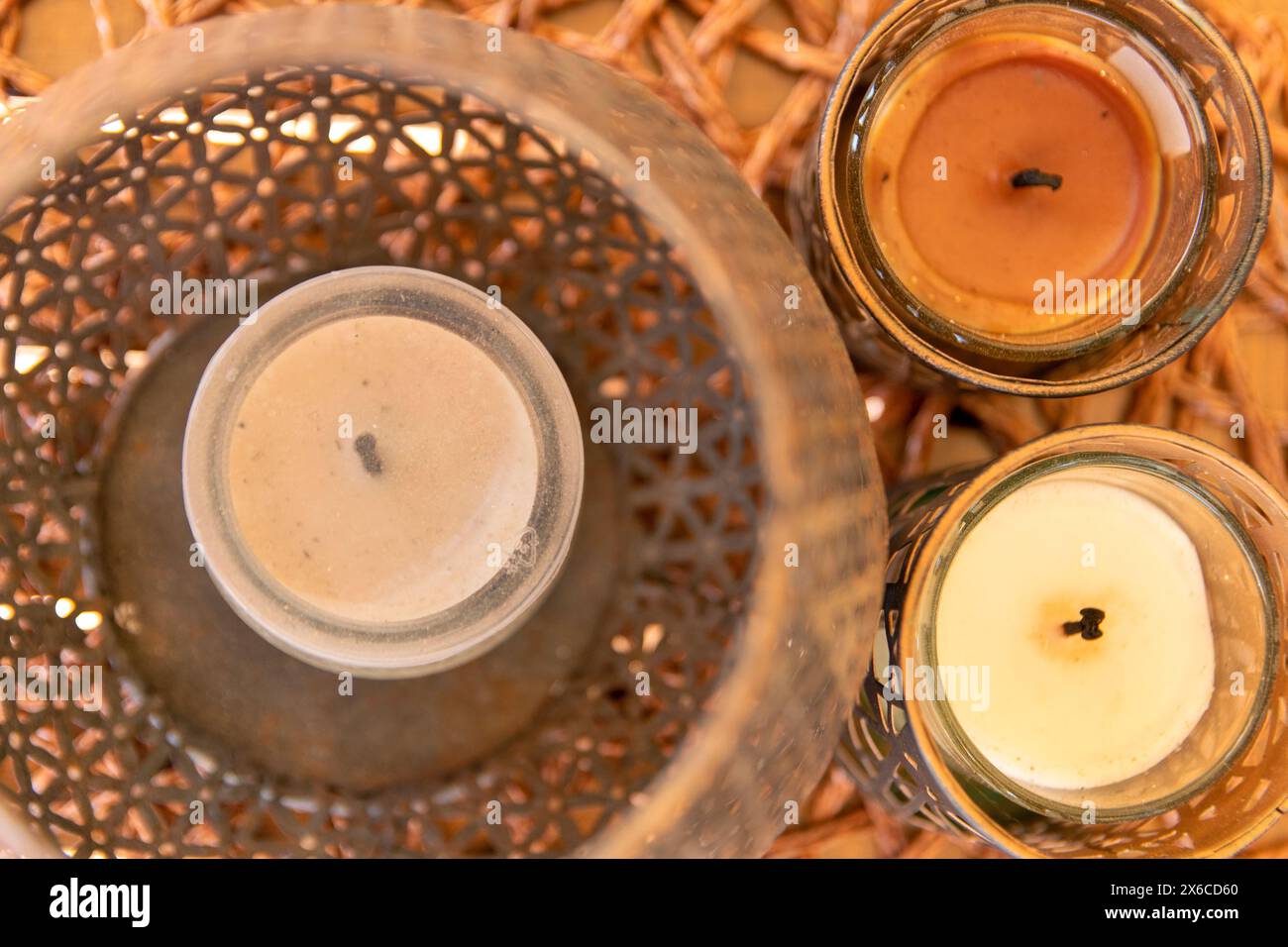 Vista ravvicinata di tre candele inserite in un cestello decorativo. Foto Stock