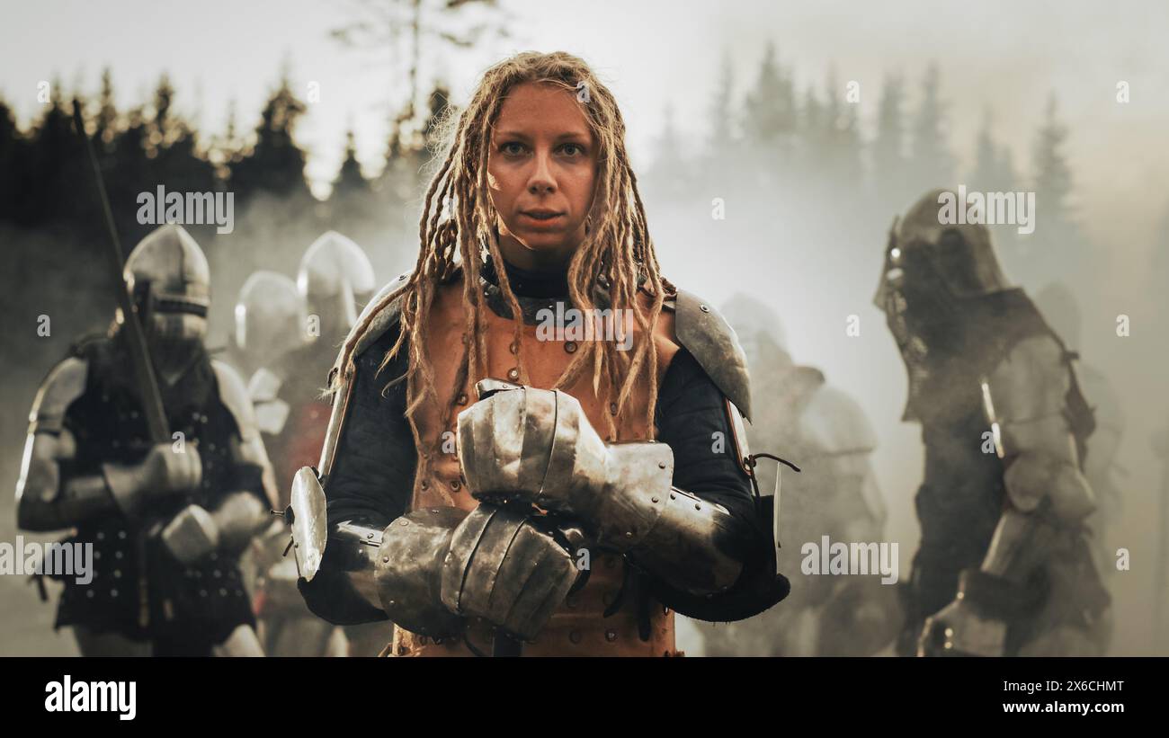 Epico campo di battaglia: Ritratto della potente leader donna guerriera che tiene in mano la spada, pronto per la battaglia. Woman Knight General in Dark Age Medieval War Against Invasion. Drammatica, cinematografica, rievocazione storica Foto Stock