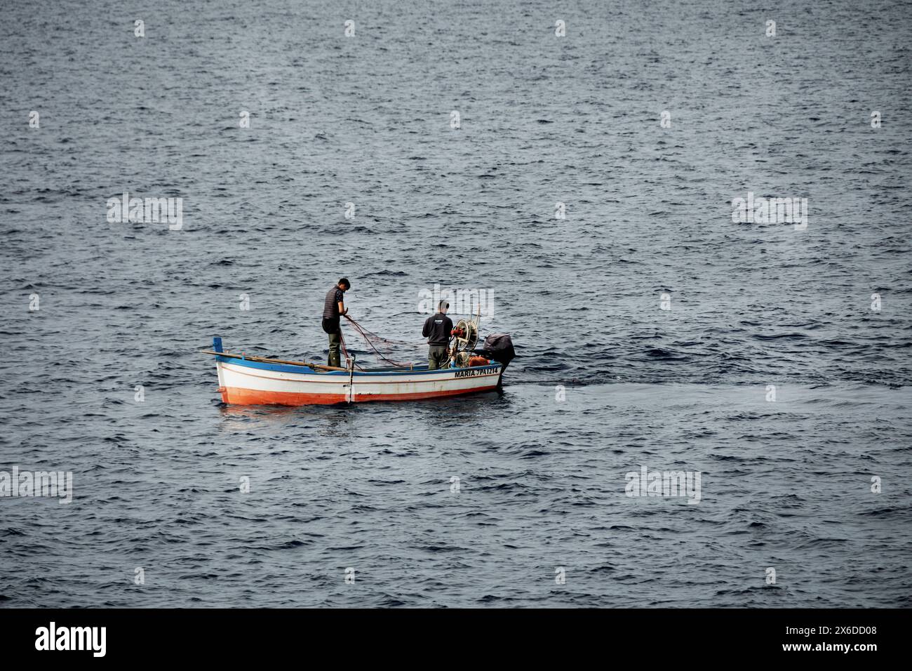 Due uomini che pescano da una piccola barca a motore al largo di Silicy, Italia, aprile 2024 Foto Stock