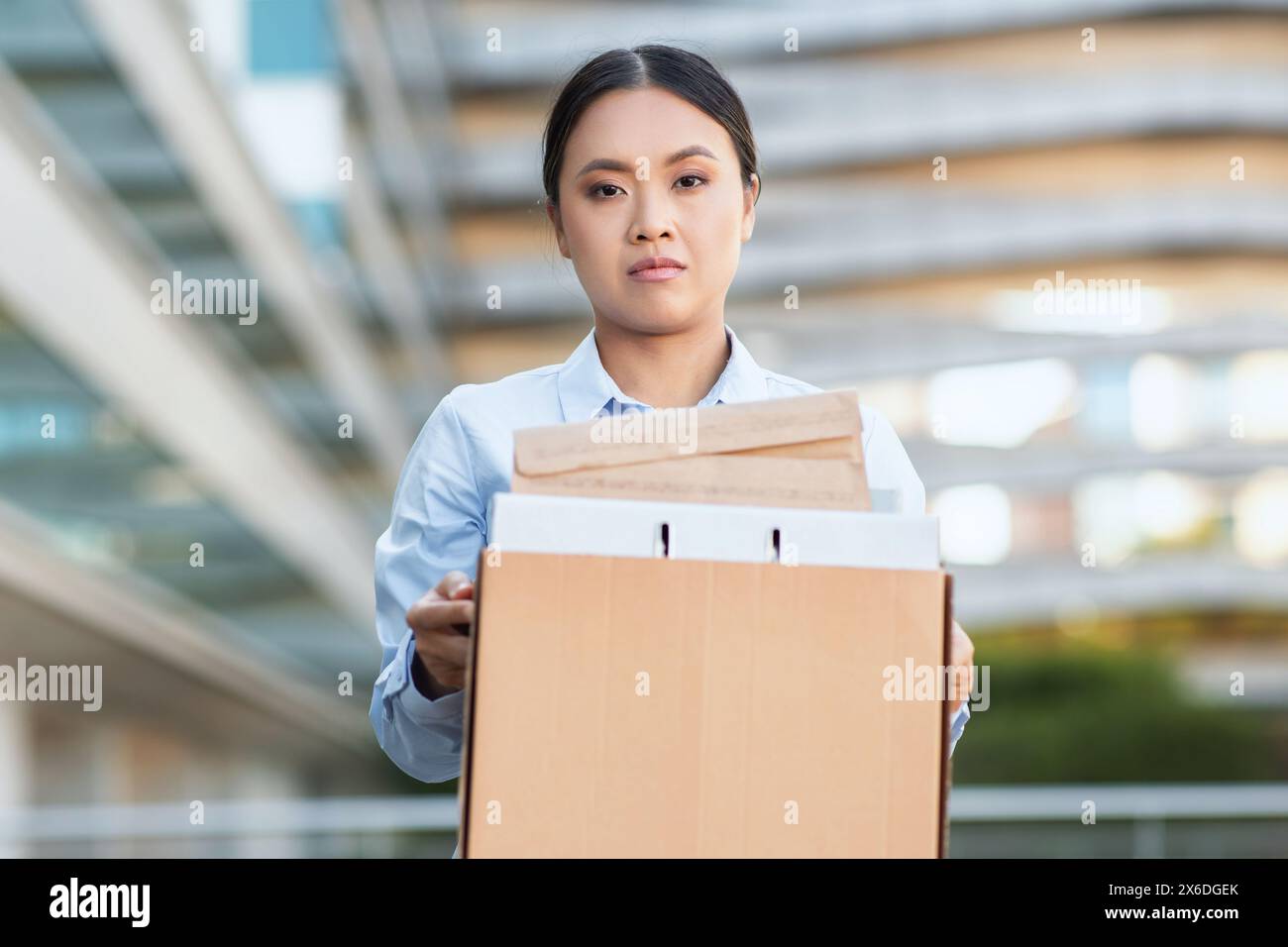 La triste signora cinese e' stata licenziata, tenendo la scatola con i suoi effetti personali Foto Stock
