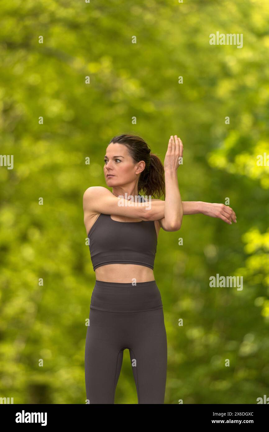 donna in forma che fa esercizi di stretching del braccio nel parco Foto Stock