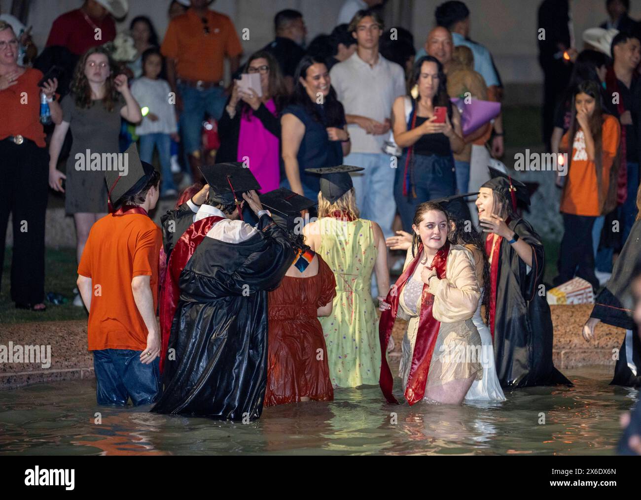 Austin Texas USA, 11 maggio 2024: La nuova University of Texas at Austin si laurea e si tuffa nella Littlefield Fountain subito dopo la cerimonia di inizio tenutasi nelle vicinanze dello stadio di football della scuola. La dunk celebrativa è una tradizione universitaria di lunga data. ©Bob Daemmrich Foto Stock