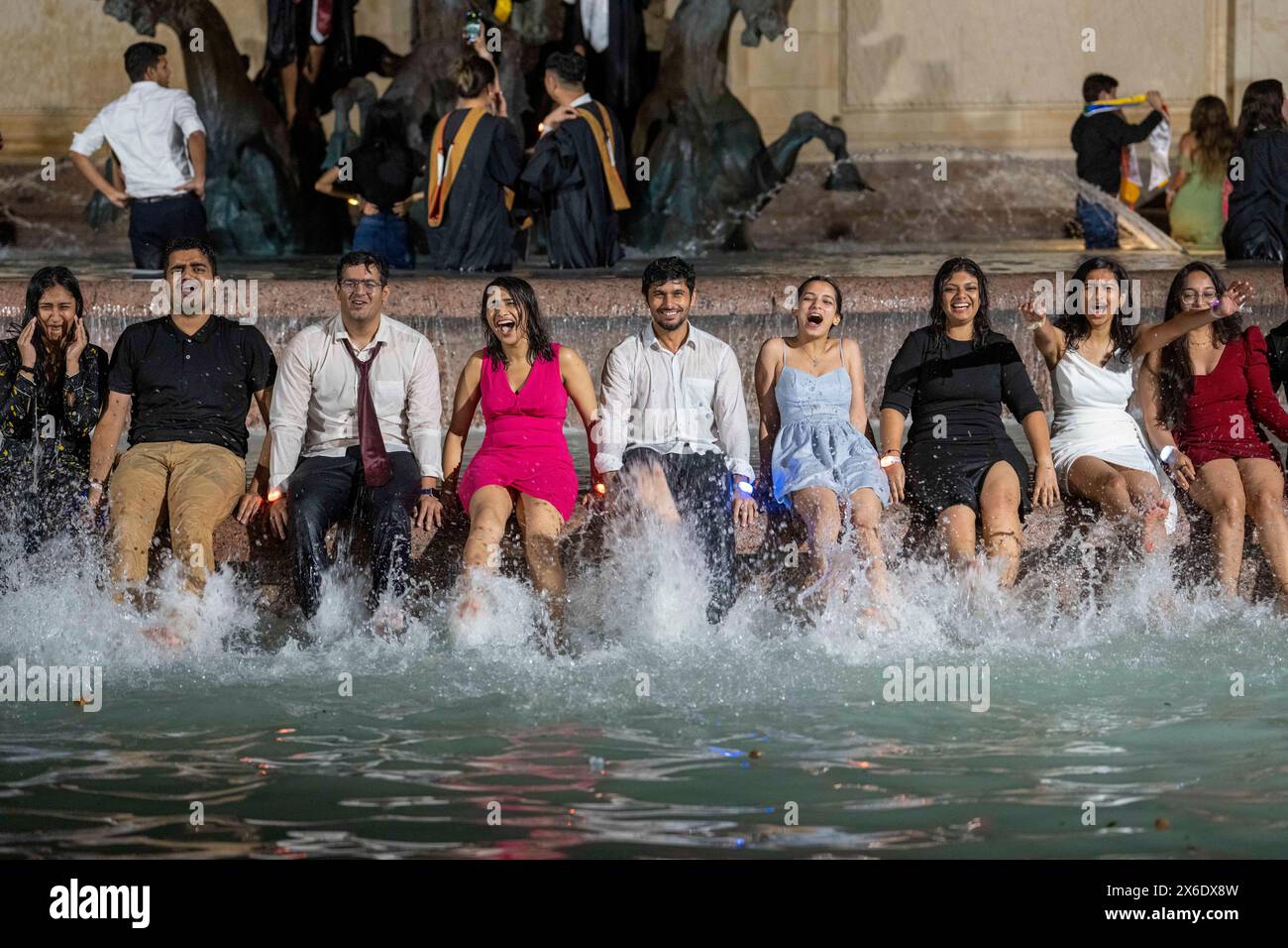 Austin Texas USA, 11 maggio 2024: La nuova University of Texas at Austin si laurea nella Littlefield Fountain subito dopo la cerimonia di inizio tenutasi nelle vicinanze dello stadio di football della scuola. La dunk celebrativa è una tradizione universitaria di lunga data. ©Bob Daemmrich Foto Stock