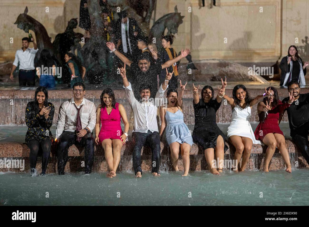 Austin Texas USA, 11 maggio 2024: La nuova University of Texas at Austin si laurea nella Littlefield Fountain subito dopo la cerimonia di inizio tenutasi nelle vicinanze dello stadio di football della scuola. La dunk celebrativa è una tradizione universitaria di lunga data. ©Bob Daemmrich Foto Stock