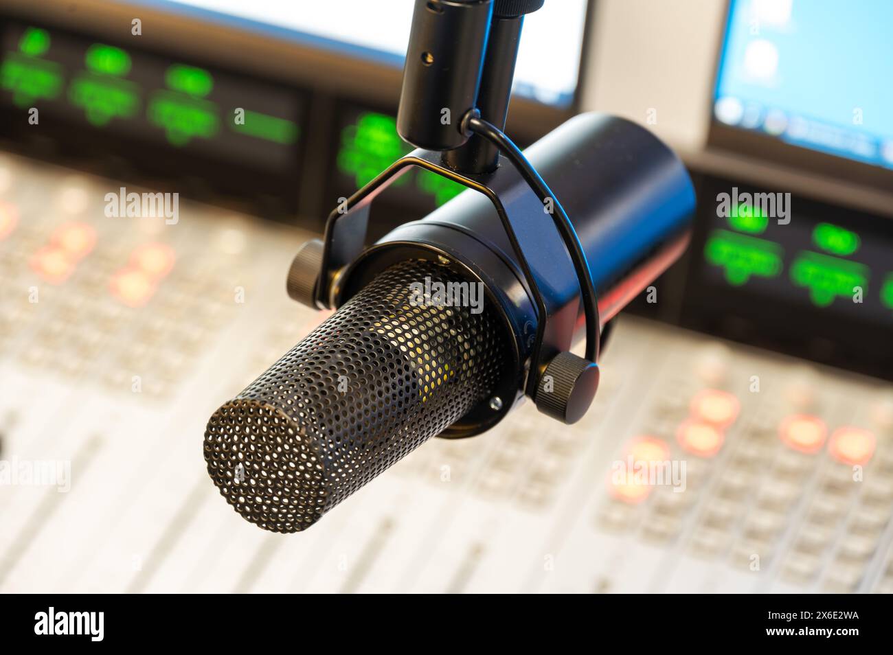 Microfono professionale in studio radio, vista ravvicinata con console di mixaggio in background, ideale per la registrazione e la trasmissione di podcast Foto Stock