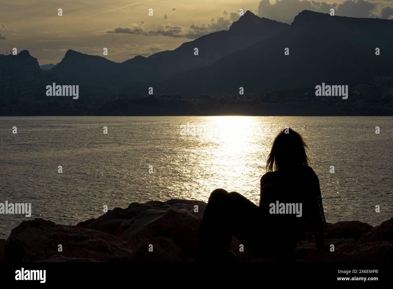 Questa straordinaria immagine cattura la silhouette di una donna in un momento di contemplazione pacifica. Foto Stock