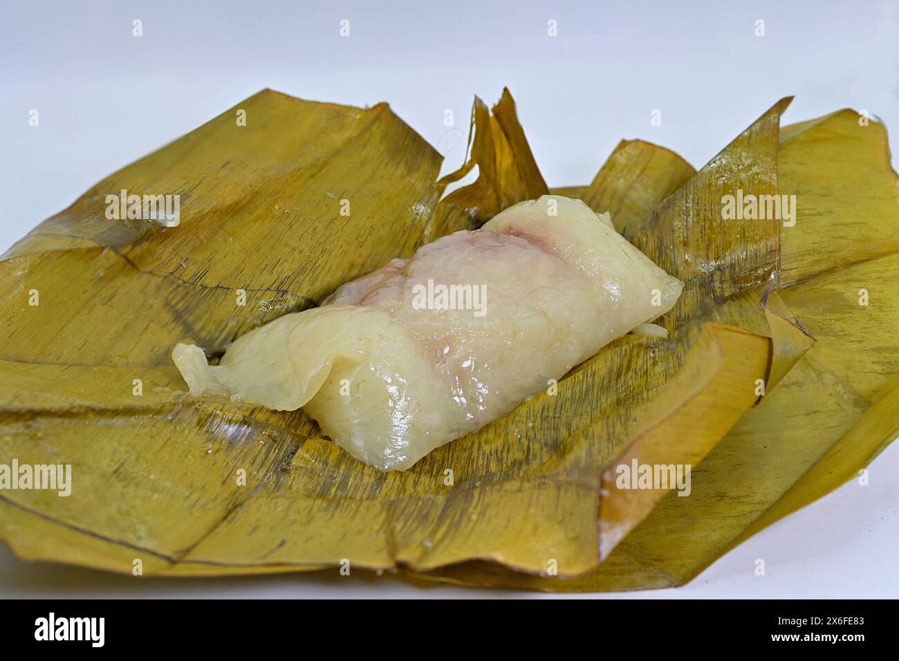 Khao tom mat, un popolare dolce tailandese fatto di riso glutinoso o appiccicoso al vapore, srotolato, su foglie di banana Foto Stock