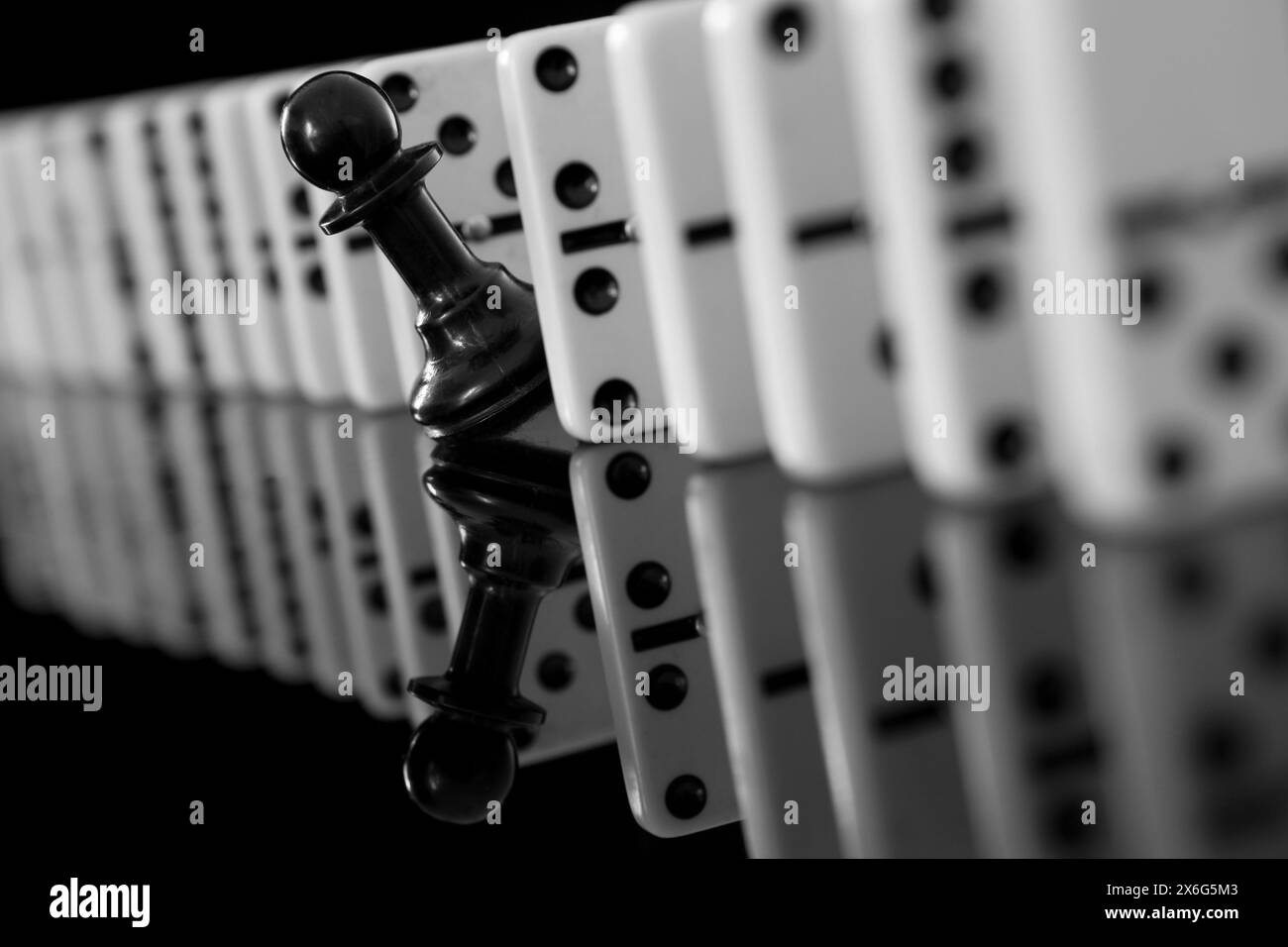 Primo piano di una pedina scacchiera nera tra pezzi di domino Foto Stock