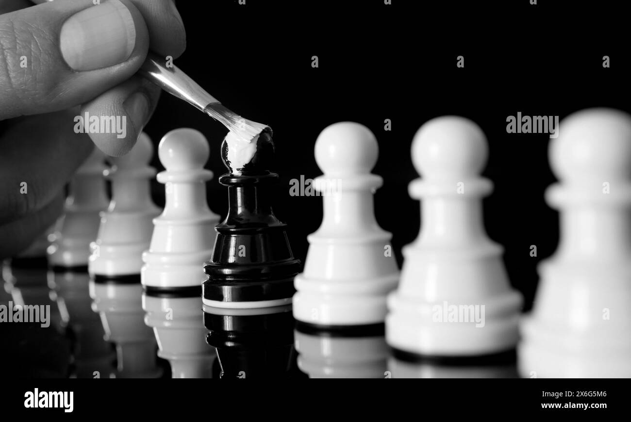 Primo piano del pedone nero dipinto di bianco come il resto delle pedine. Concetto di auto-identità Foto Stock