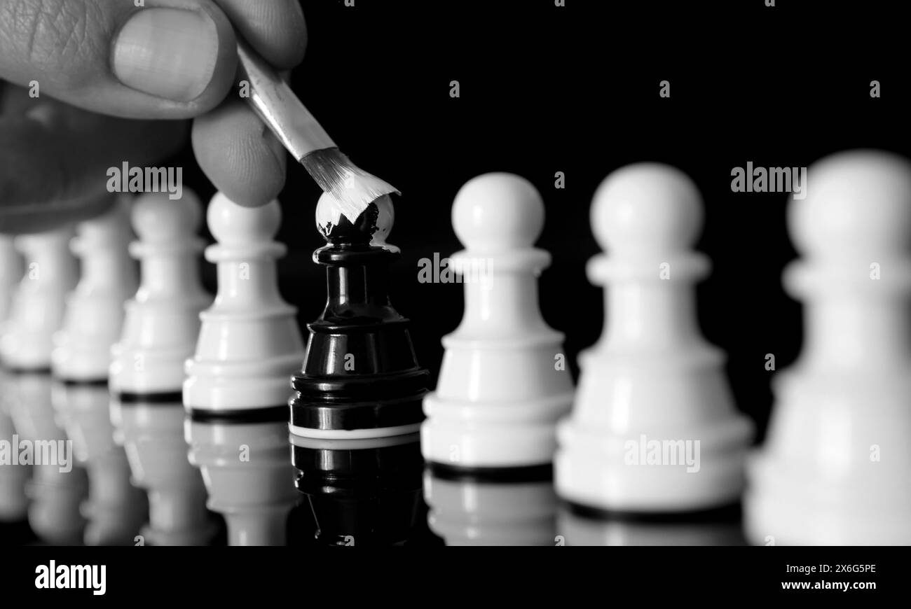 Primo piano del pedone nero dipinto di bianco come il resto delle pedine. Concetto di auto-identità Foto Stock