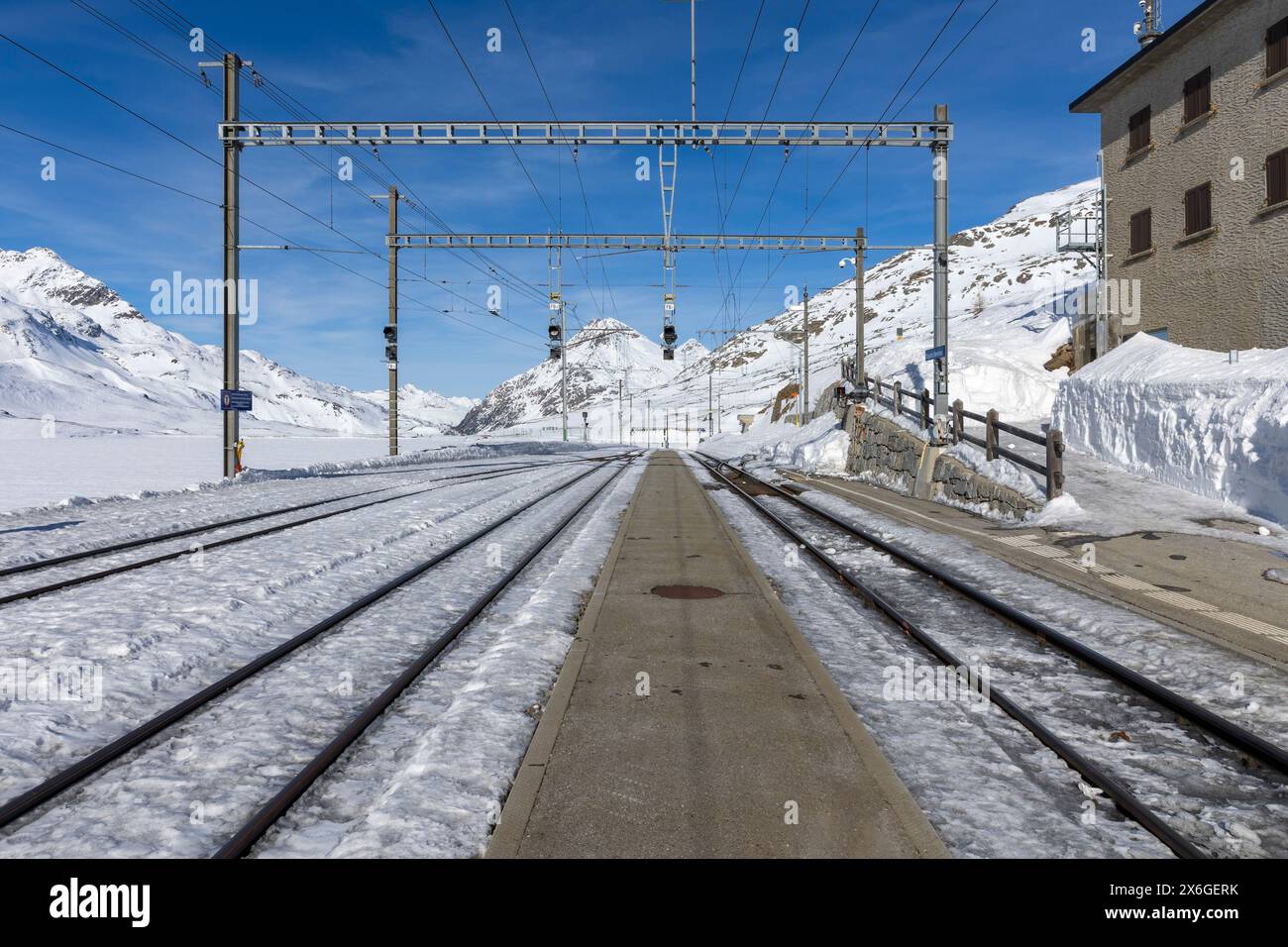 Stazione ferroviaria sul passo Bernina in Svizzera. Vista frontale dalla piattaforma ferroviaria e dai binari che appaiono dalla neve. Nessuno dentro Foto Stock