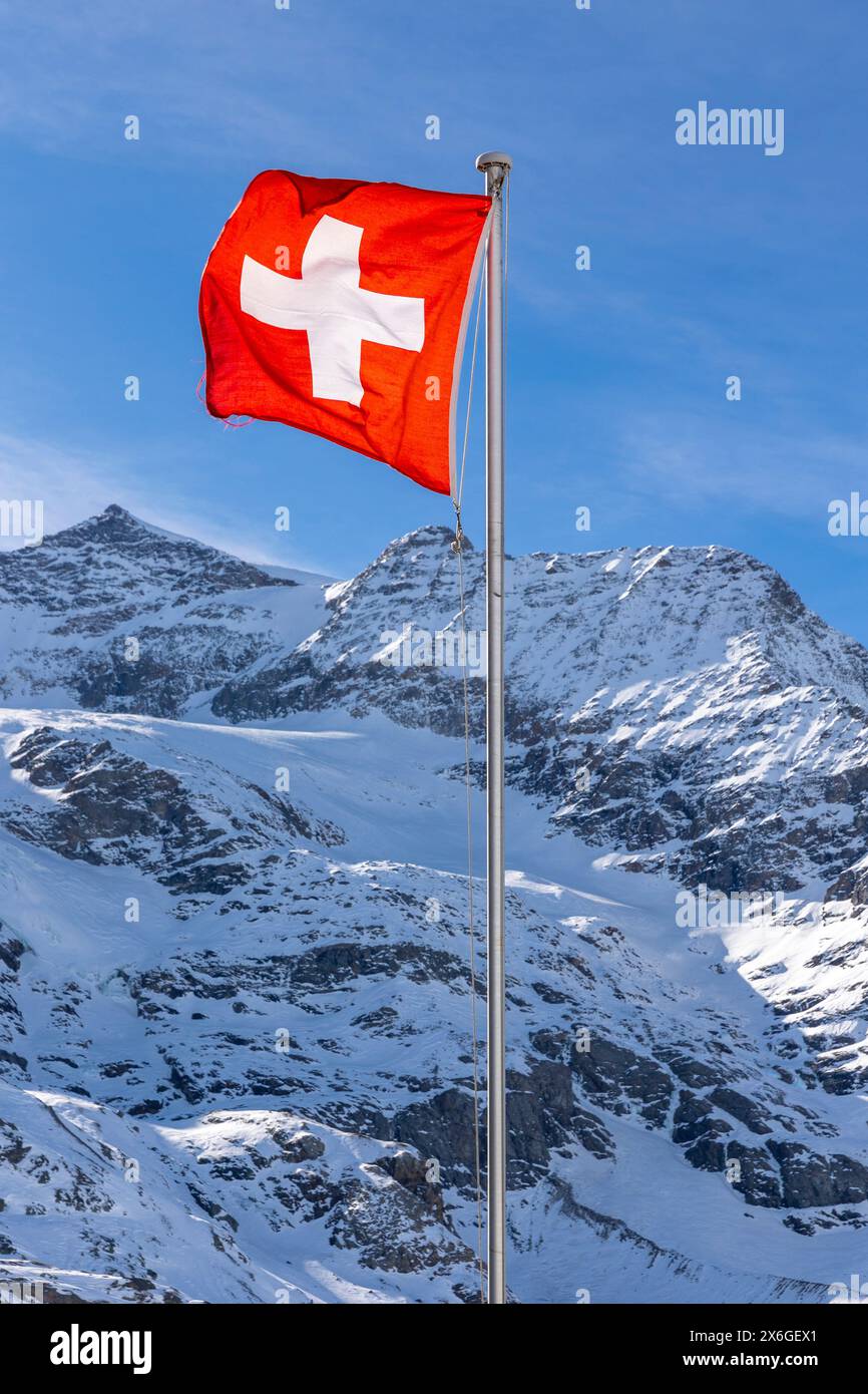 Particolare della bandiera svizzera che sventolava molto forte a causa del forte vento. Sullo sfondo la montagna innevata. Nessuno dentro Foto Stock