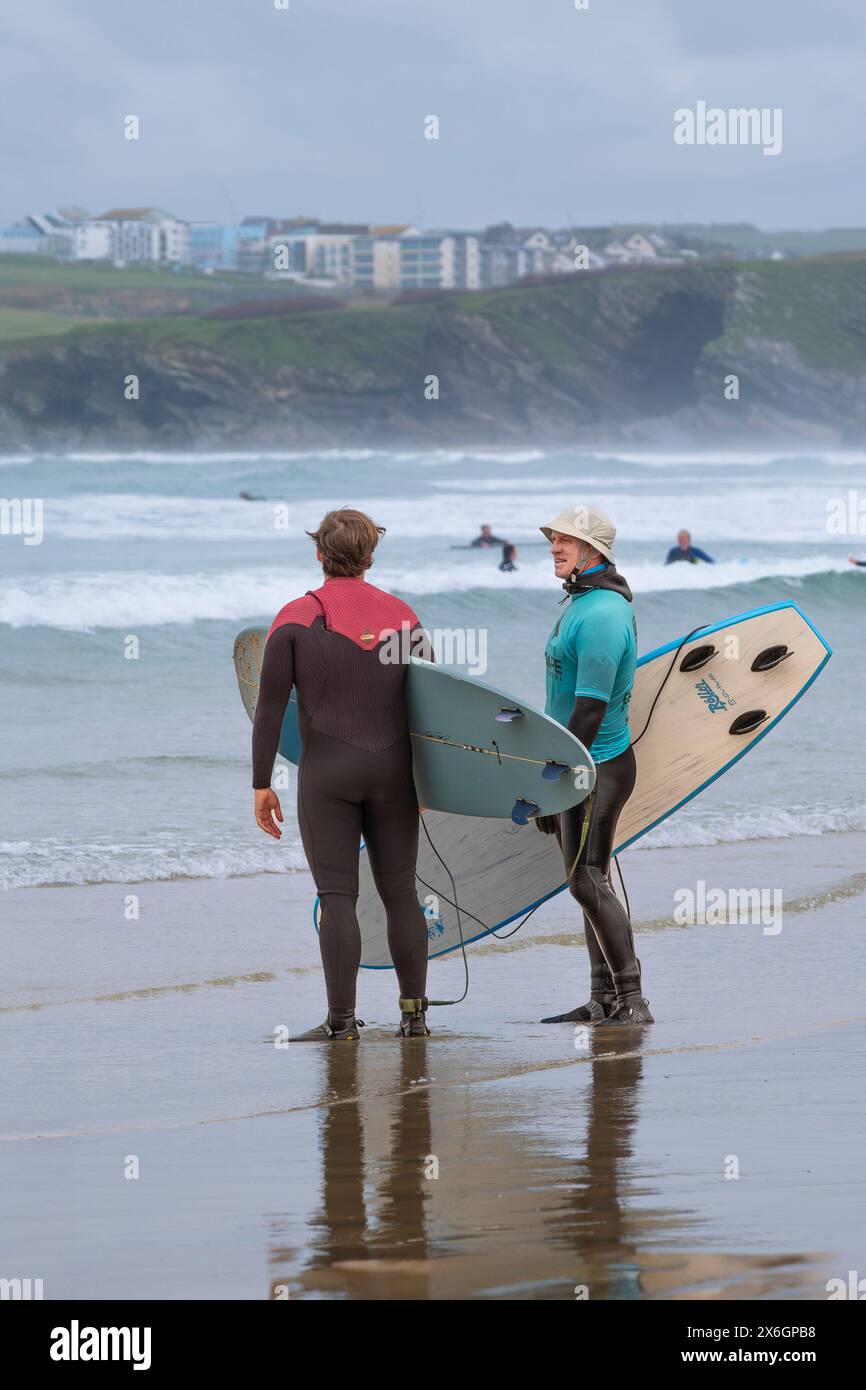 Un insegnante di surf della Escape Surf School che parla con un altro surfista sulla spiaggia di Towan a Newquay, in Cornovaglia, nel Regno Unito. Foto Stock