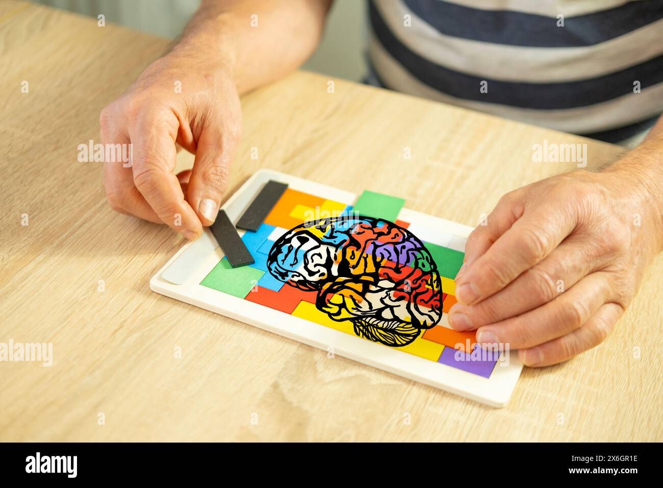 Tenendo la mente attiva mano anziana maschile manipola puzzle di legno colorato, salute del cervello e benessere mentale, formazione cognitiva, assistenza anziani Foto Stock