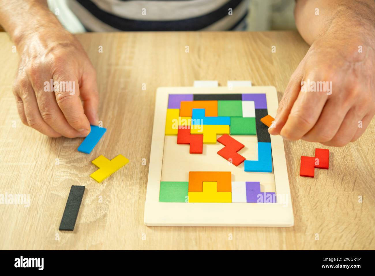 mano maschile manipola puzzle di legno colorato, vecchio anziano che compone forme geometriche, salute del cervello e benessere mentale, prevenire la demenza e. Foto Stock