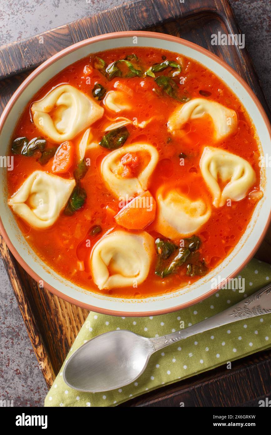 Tortellini di pomodoro italiano, zuppa di pasta con verdure e spinaci da vicino in un piatto sul tavolo. Vista dall'alto verticale Foto Stock