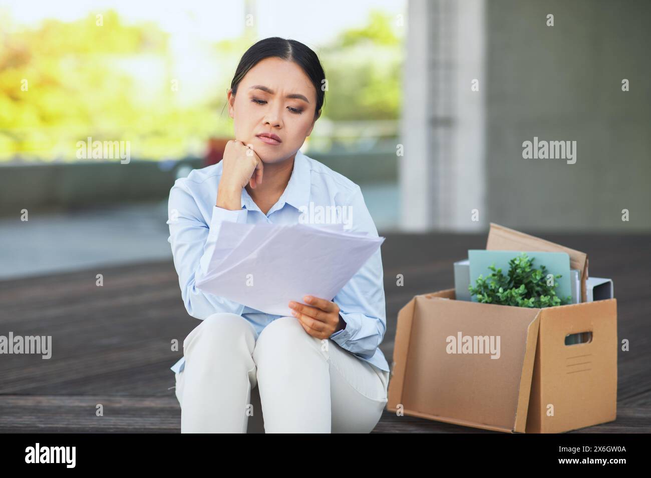 Una donna disoccupata seduta con le sue proprietà al botteghino Foto Stock