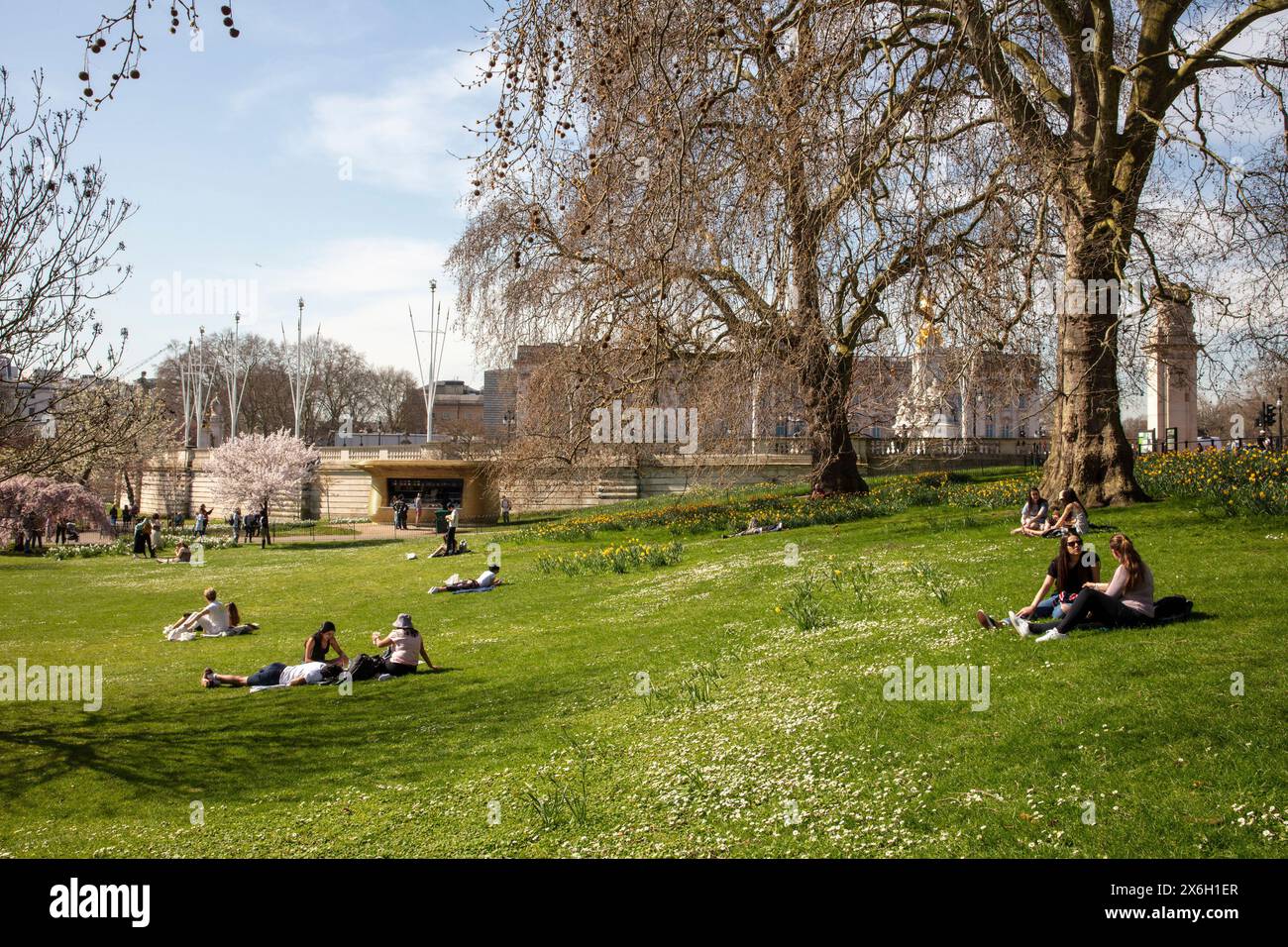 Le persone si siedono nel parco di fronte a Buckingham Palace e al chiosco del caffè. The Horseshoe Kiosk, The Royal Parks, Westminster, Regno Unito. Architec Foto Stock