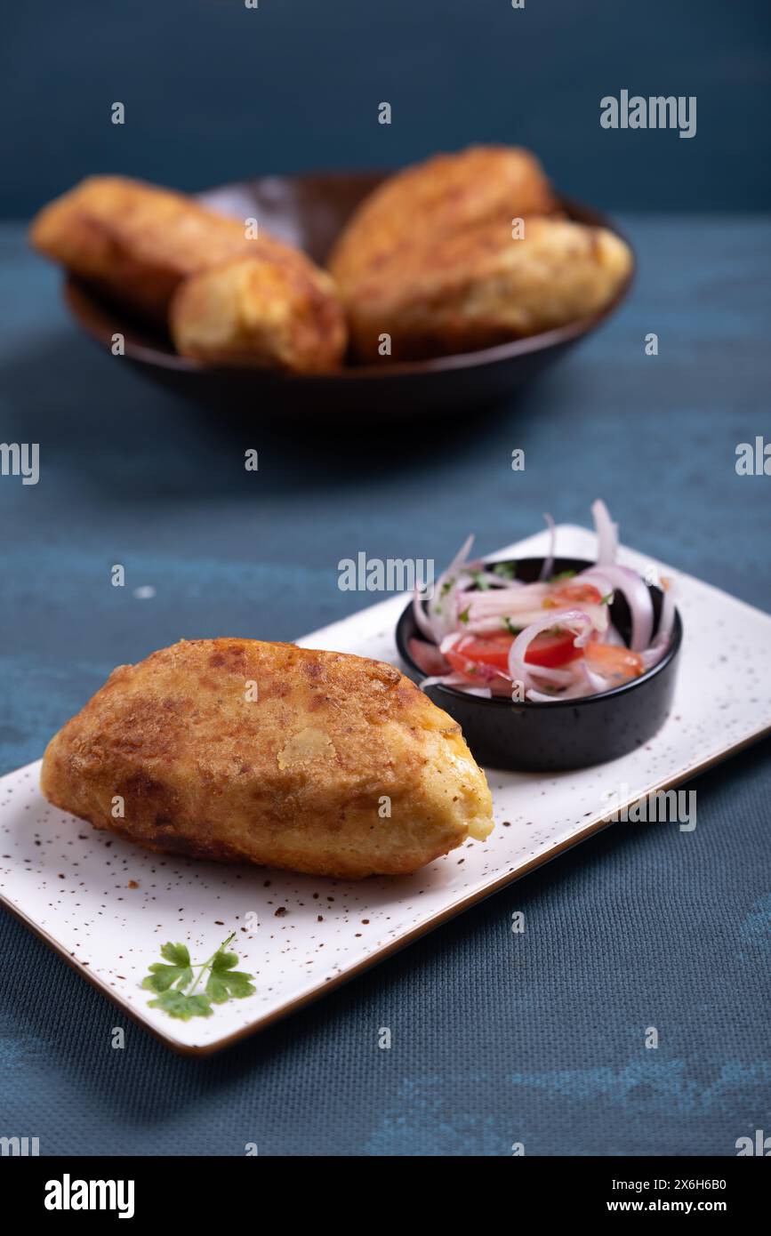 Vista dall'alto di una patata croccante con ripieno di carne all'interno, accompagnata da una cipolla e insalata di pomodoro. Foto Stock