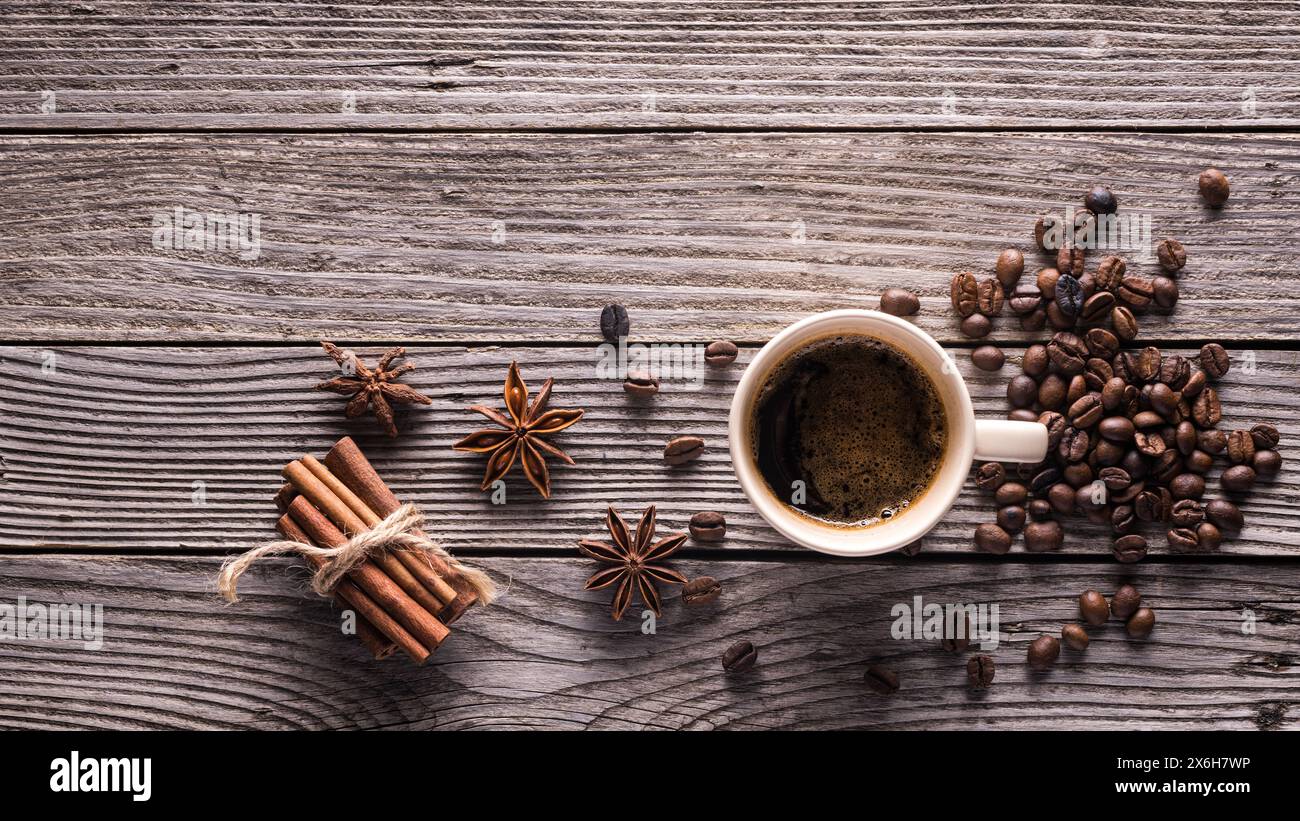 tazza in vetro con vista dall'alto con espresso, chicchi di caffè, anice stellato e bastoncini di cannella su sfondo grigio in legno con spazio vuoto sopra la vista Foto Stock