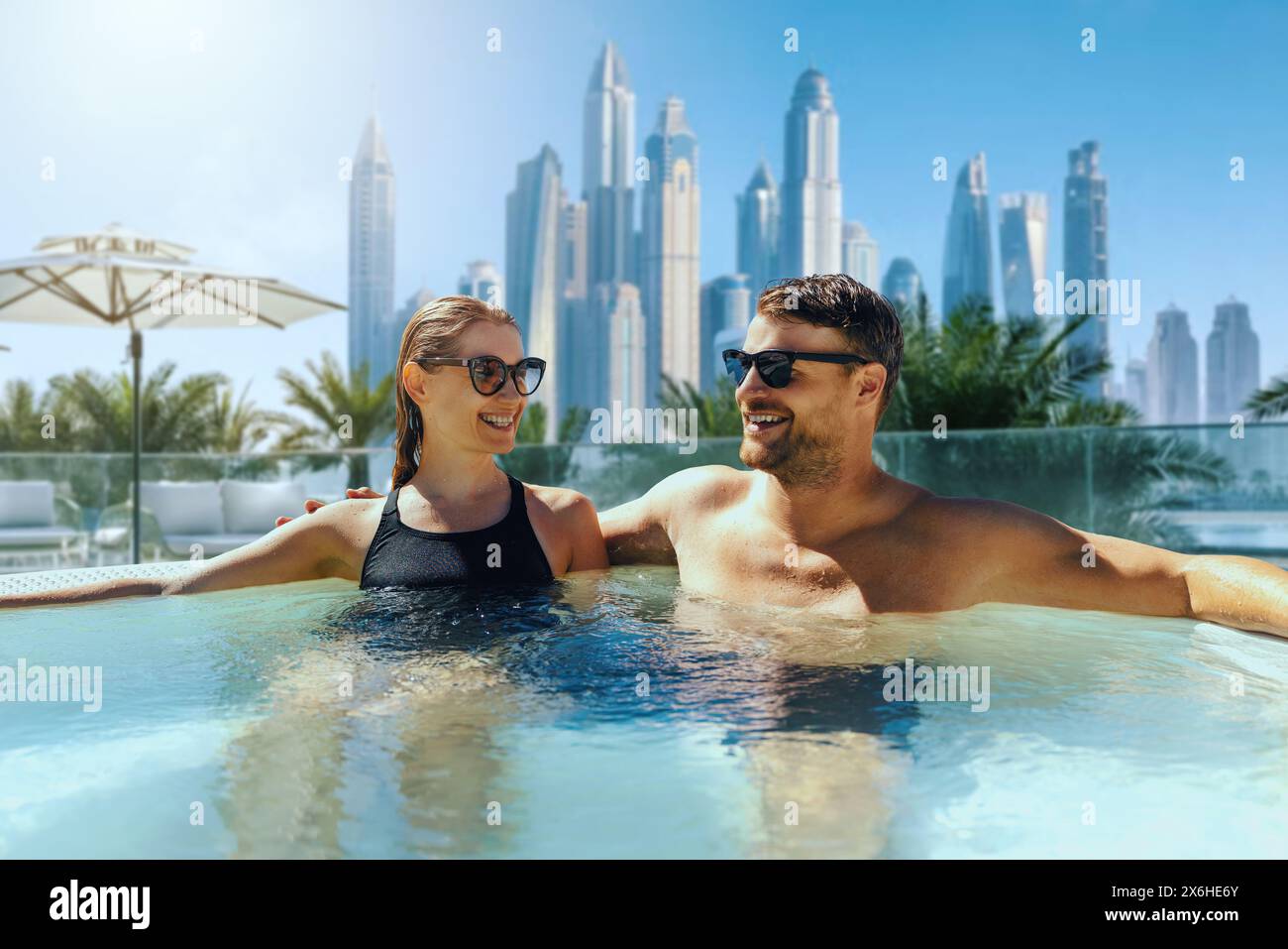 Giovani coppie felici che si rilassano nella vasca idromassaggio all'aperto dell'hotel di Dubai. vacanza di lusso, viaggio breve Foto Stock
