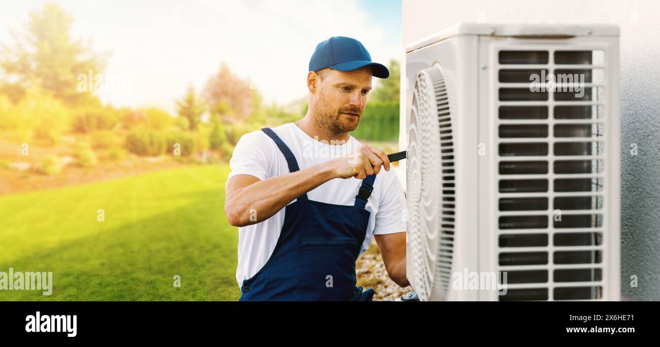 tecnico che lavora sull'impianto di climatizzazione dell'abitazione o sull'unità esterna della pompa di calore. Assistenza, manutenzione e riparazione HVAC. banner con spazio di copia Foto Stock