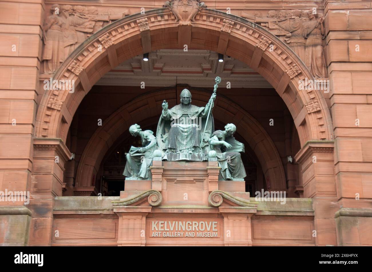 Statua di St Mango; Kelvin Grove Art Gallery and Museum, Glasgow, Scozia, Regno Unito - Vescovo St Mungo; due femmine, una lettura e una che suona un musical i. Foto Stock