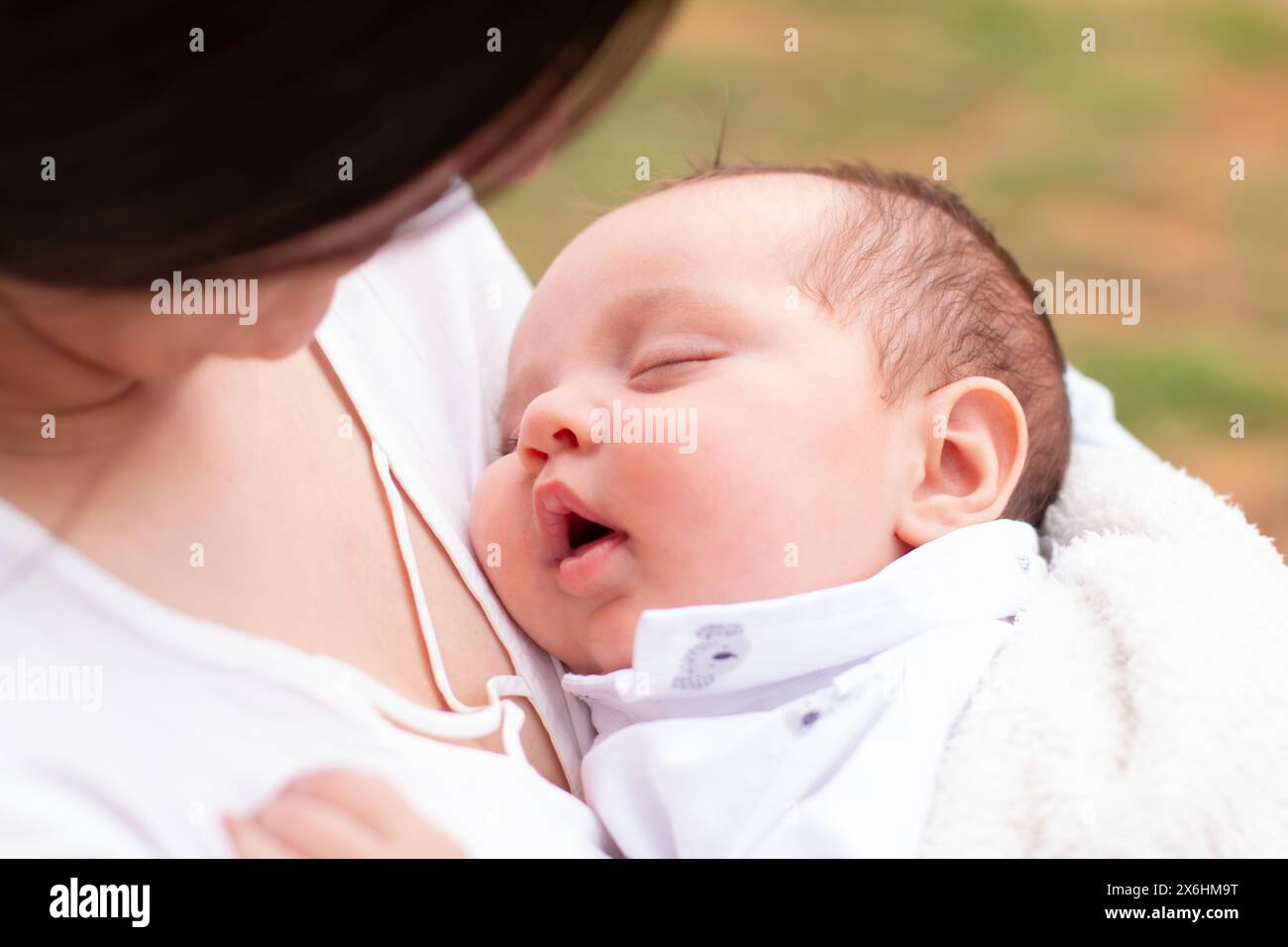 stile di vita: primo piano del viso del bambino addormentato tra le braccia della madre Foto Stock