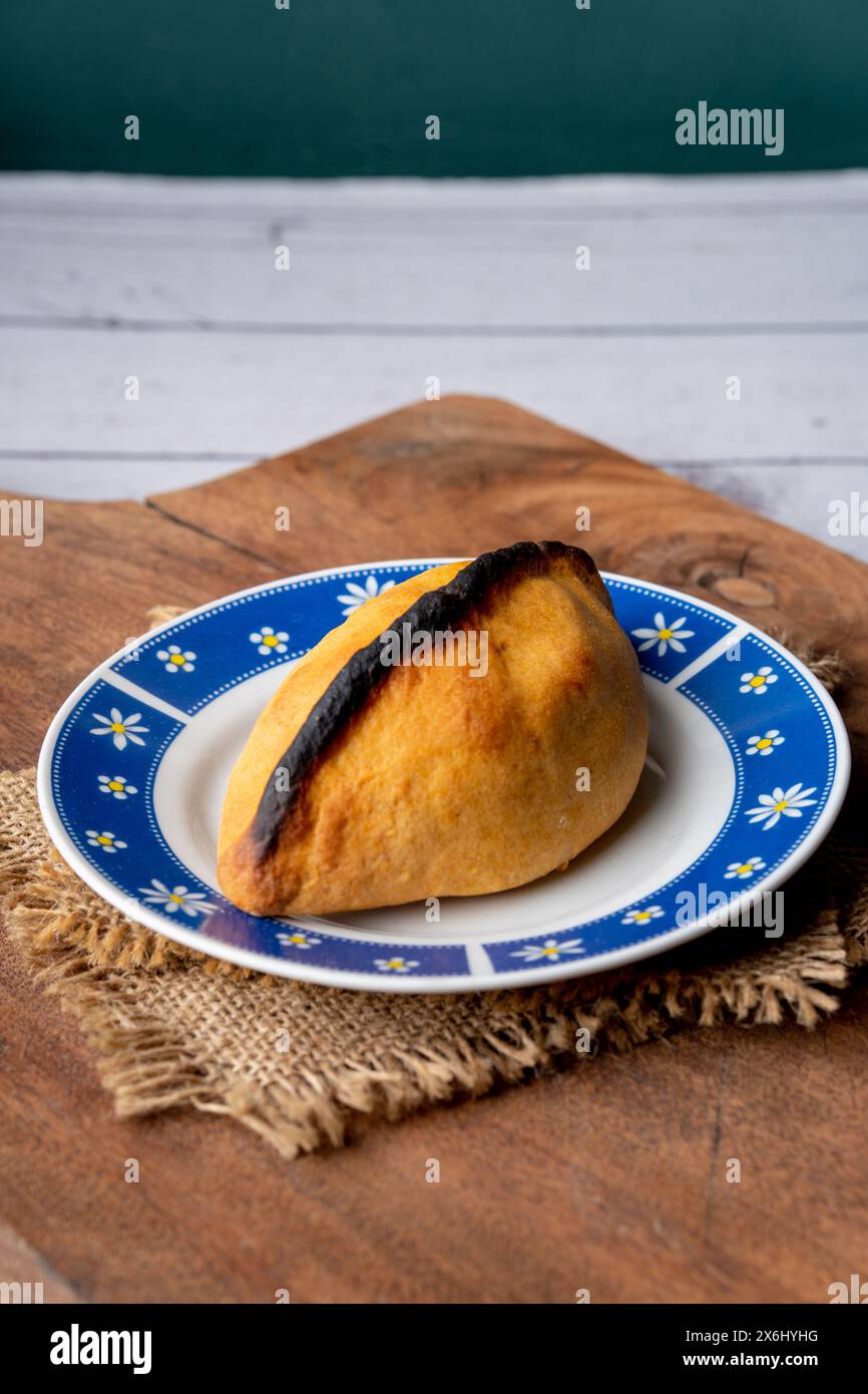 Salteña, tipica empanada boliviana in un piatto colorato su una tavola bianca rustica. tradizione boliviana. cibo di strada, piano orizzontale. Foto Stock