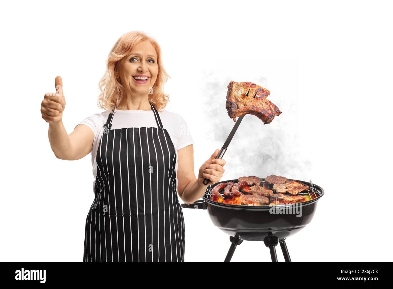 Donna che grigia la carne su un barbecue e gesti i pollice isolato su sfondo bianco Foto Stock