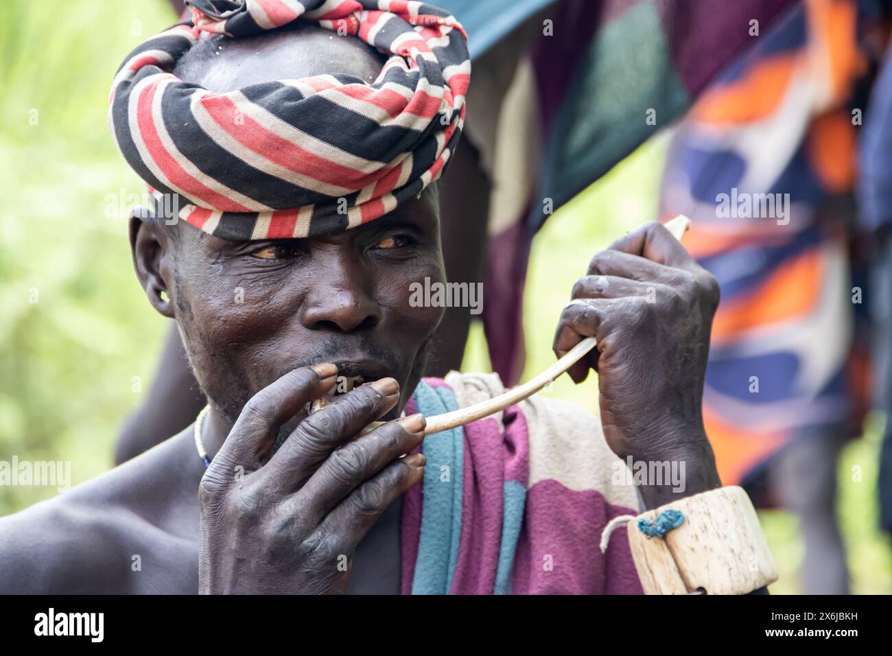 I membri della tribù Mursi in Etiopia mangiano carne di pesce fresco cacciata, raccolta intorno a un fuoco, gustando un pasto tradizionale nel loro ambiente naturale Foto Stock