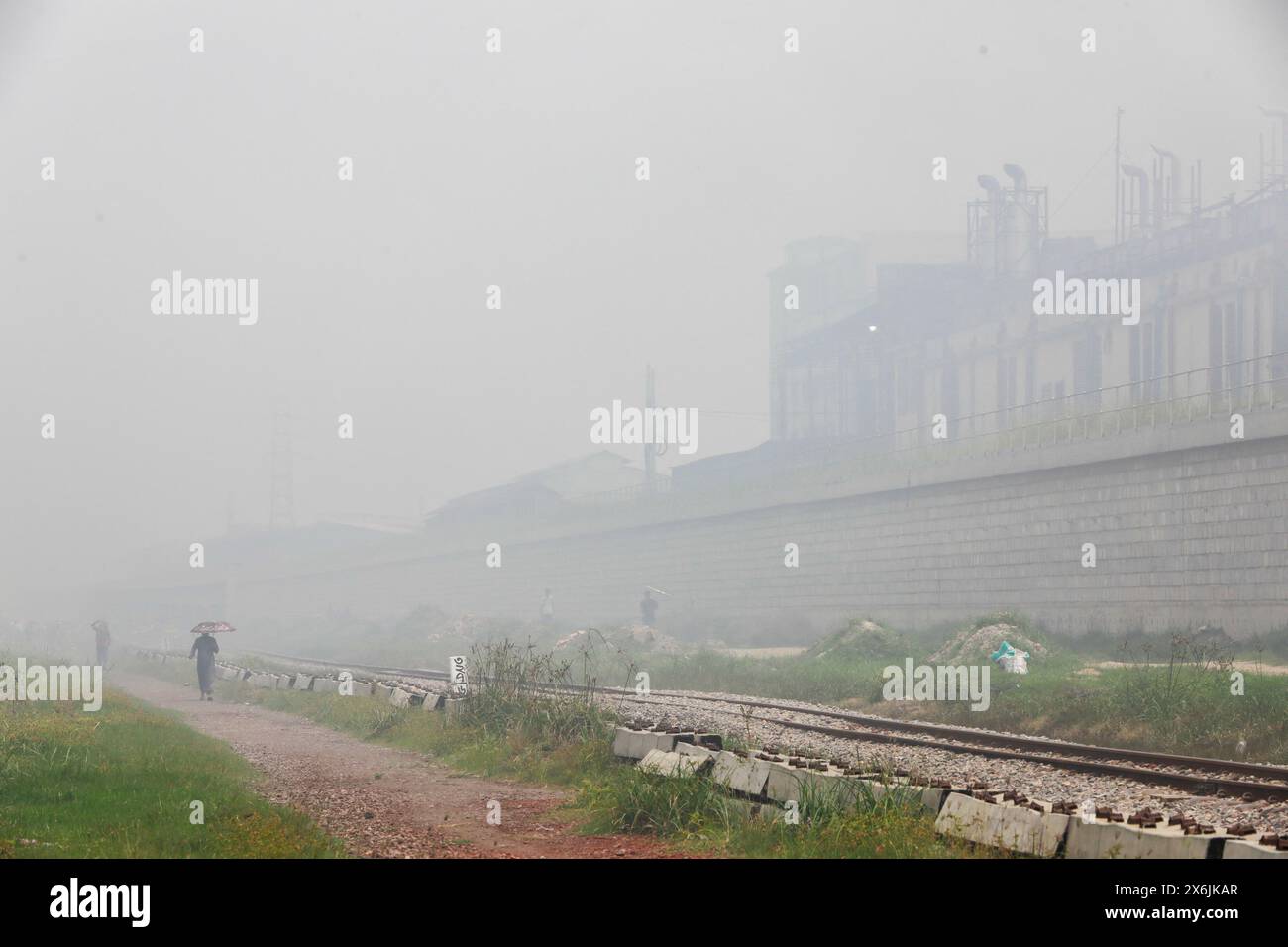 Dacca, Bangladesh. 15 maggio 2024. La gente passa un'area industriale mentre il fumo sale dai mulini rilaminati a Shyampur, a Dacca, Bangladesh, 15 maggio 2024. Secondo uno studio della Banca mondiale, il Bangladesh deve affrontare un elevato livello di inquinamento atmosferico, che costa circa il 9% del PIL all'anno. La maggior parte dei laminatoi in acciaio all'interno e intorno alla capitale sono stati eseguiti senza il necessario sistema di controllo dell'inquinamento atmosferico che poneva un rischio di inquinamento atmosferico e di pericolo per la salute. Foto di Suvra Kanti Das/ABACAPRESS. COM credito: Abaca Press/Alamy Live News Foto Stock