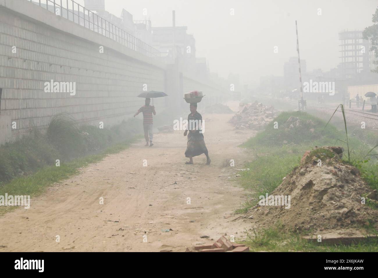 Dacca, Bangladesh. 15 maggio 2024. La gente passa un'area industriale mentre il fumo sale dai mulini rilaminati a Shyampur, a Dacca, Bangladesh, 15 maggio 2024. Secondo uno studio della Banca mondiale, il Bangladesh deve affrontare un elevato livello di inquinamento atmosferico, che costa circa il 9% del PIL all'anno. La maggior parte dei laminatoi in acciaio all'interno e intorno alla capitale sono stati eseguiti senza il necessario sistema di controllo dell'inquinamento atmosferico che poneva un rischio di inquinamento atmosferico e di pericolo per la salute. Foto di Suvra Kanti Das/ABACAPRESS. COM credito: Abaca Press/Alamy Live News Foto Stock