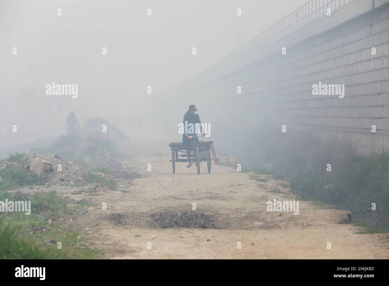 Dacca, Bangladesh. 15 maggio 2024. La gente passa un'area industriale mentre il fumo sale dai mulini rilaminati a Shyampur, a Dacca, Bangladesh, 15 maggio 2024. Secondo uno studio della Banca mondiale, il Bangladesh deve affrontare un elevato livello di inquinamento atmosferico, che costa circa il 9% del PIL all'anno. La maggior parte dei laminatoi in acciaio all'interno e intorno alla capitale sono stati eseguiti senza il necessario sistema di controllo dell'inquinamento atmosferico che poneva un rischio di inquinamento atmosferico e di pericolo per la salute. Foto di Suvra Kanti Das/ABACAPRESS. COM credito: Abaca Press/Alamy Live News Foto Stock
