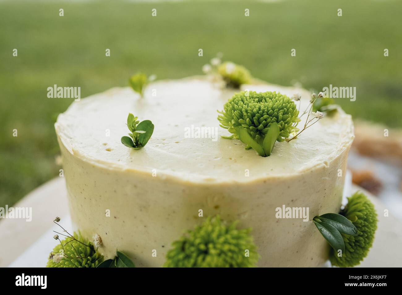 Elegante torta bianca decorata con dettagli floreali verdi Foto Stock
